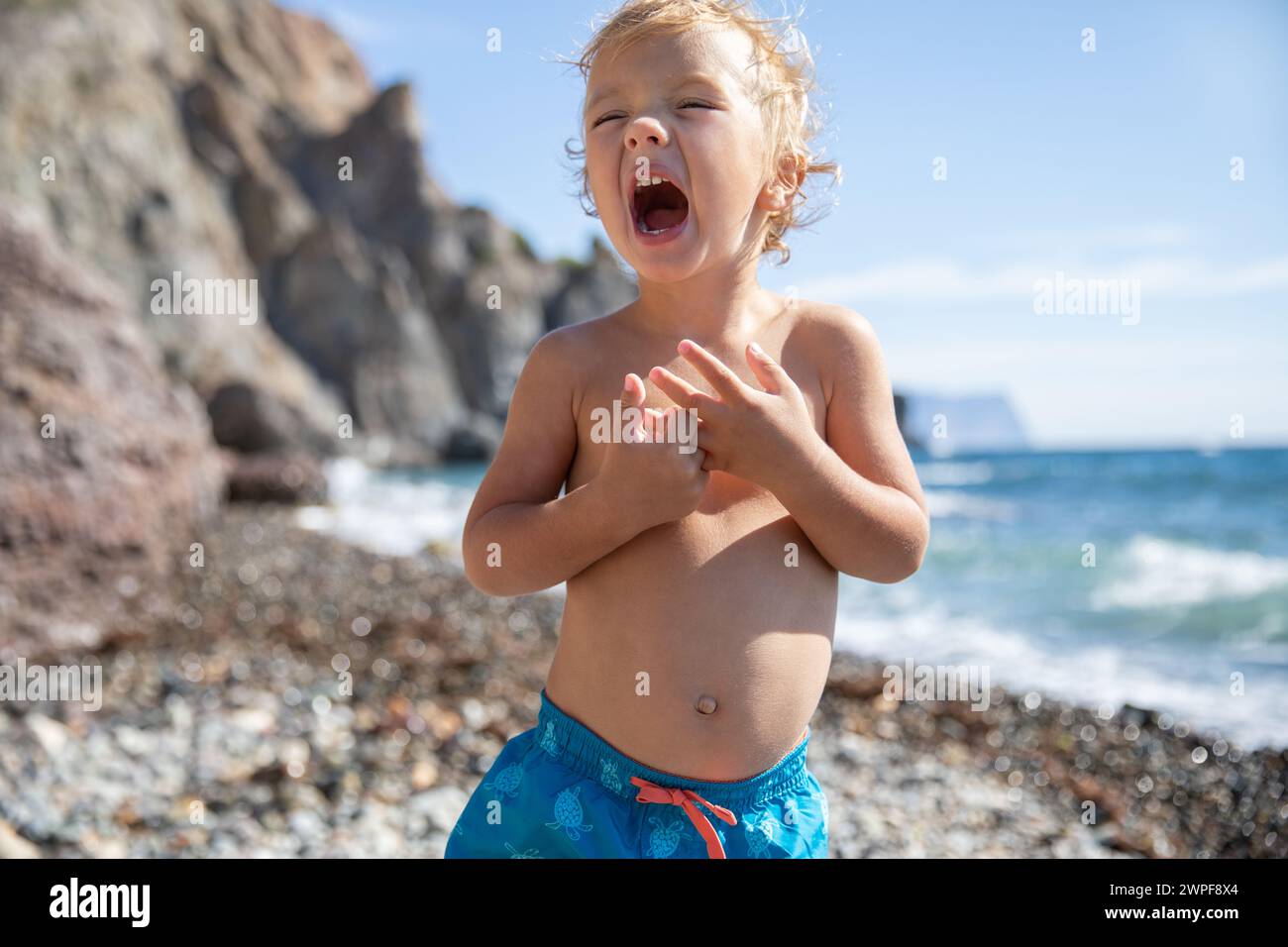 Ein wunderschönes blondes Kind 2,5 Jahre alt in Badehosen am Meer an einem sonnigen warmen Sommertag. Stockfoto