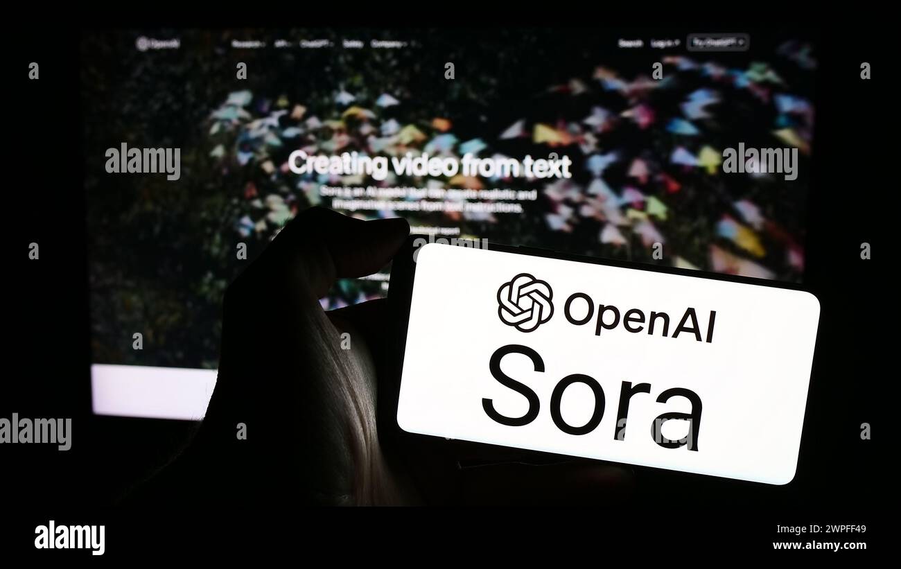 Person, die ein Mobiltelefon mit dem Logo der Text-to-Video-Modellsoftware Sora (OpenAI) vor der Unternehmenswebsite hält. Schwerpunkt auf dem Display des Telefons. Stockfoto