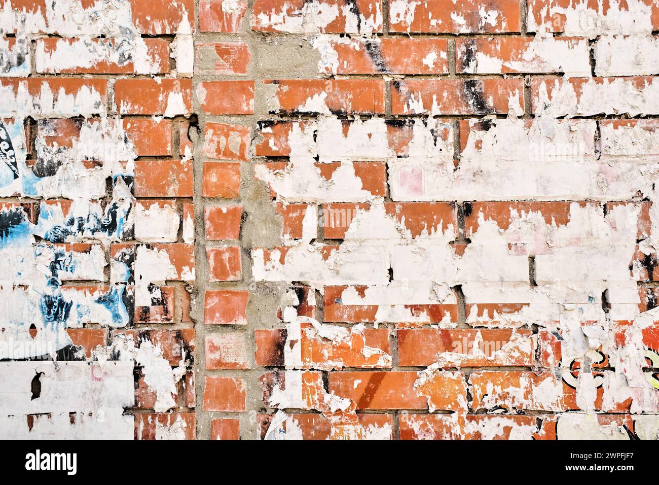 Strukturiertes, zerrissenes Posterpapier vor rustikaler Backsteinwand, urbanem Sand und Straßenmuster Stockfoto