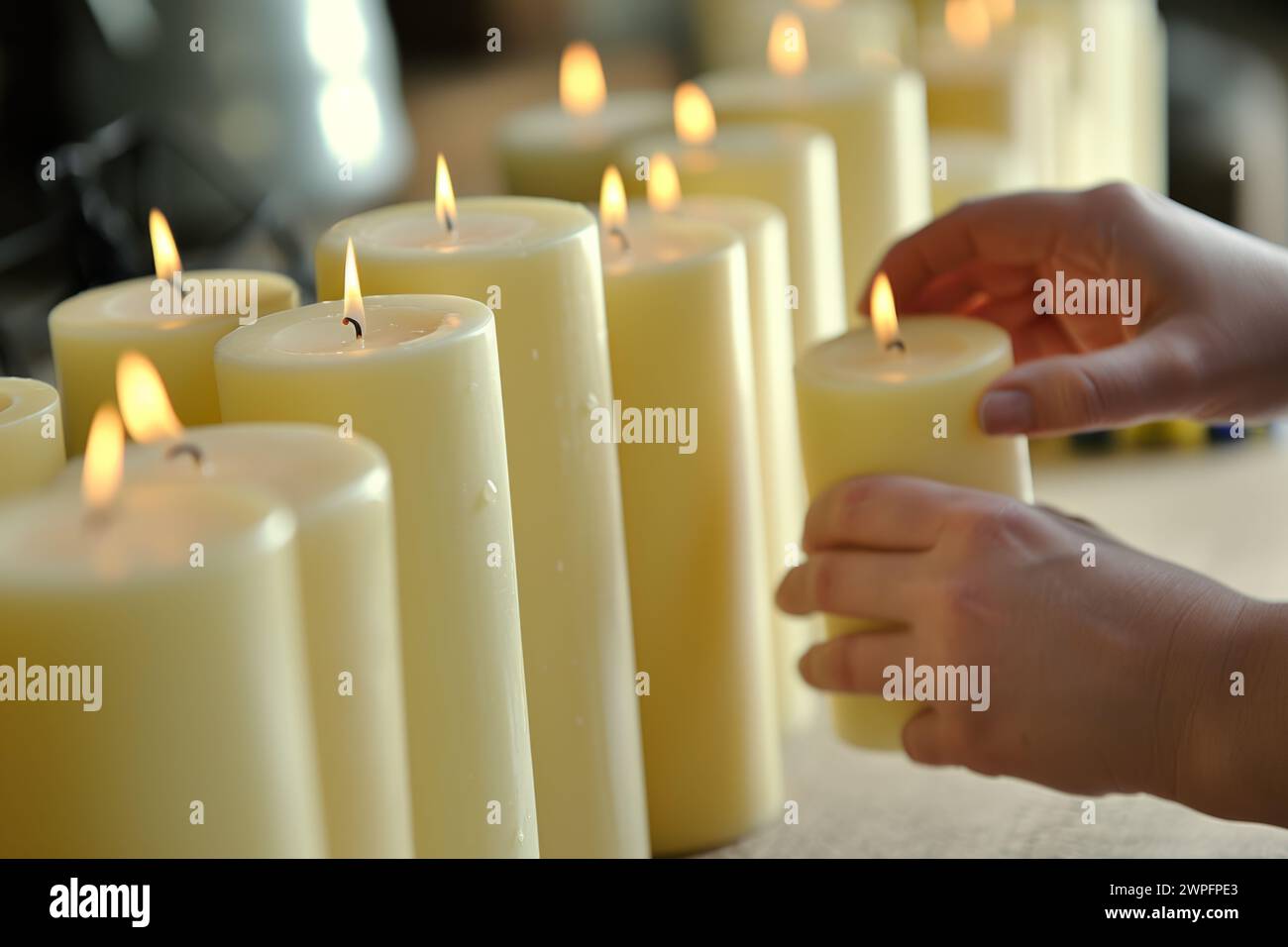 Schließen Sie oben nicht erkennbare unbekannte Person Hände setzen viele dekorative brennende Flamme Feuer Licht Glühkerzen innen Haus Wohnzimmer Wohnung Stockfoto