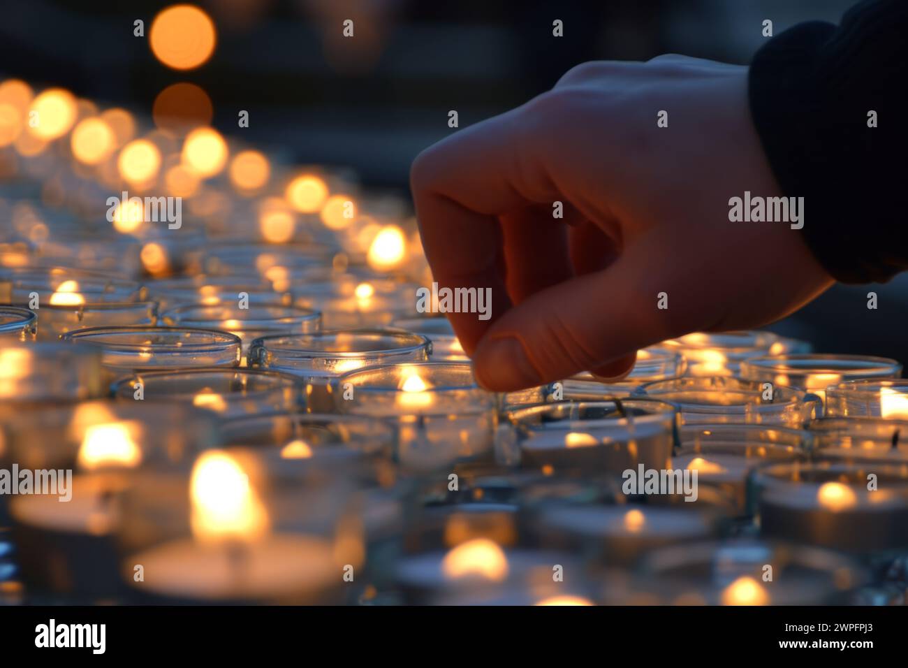 Nahaufnahme nicht erkennbare unbekannte Person Gebet männlicher Mann Hände Beleuchtung Gedenkfeier Votiv beleuchtete Kirchenkerzen Feiertage religiöse Trauer brennende Lichter Stockfoto