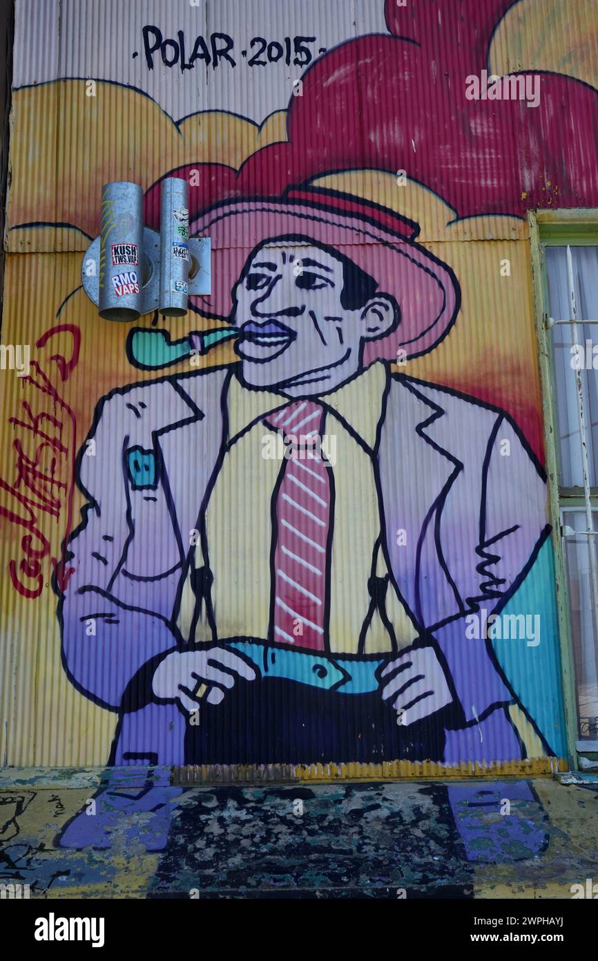Buntes Street Art Gemälde eines Mannes, der eine Pfeife raucht, auf einer gewellten Metallwand. Stockfoto