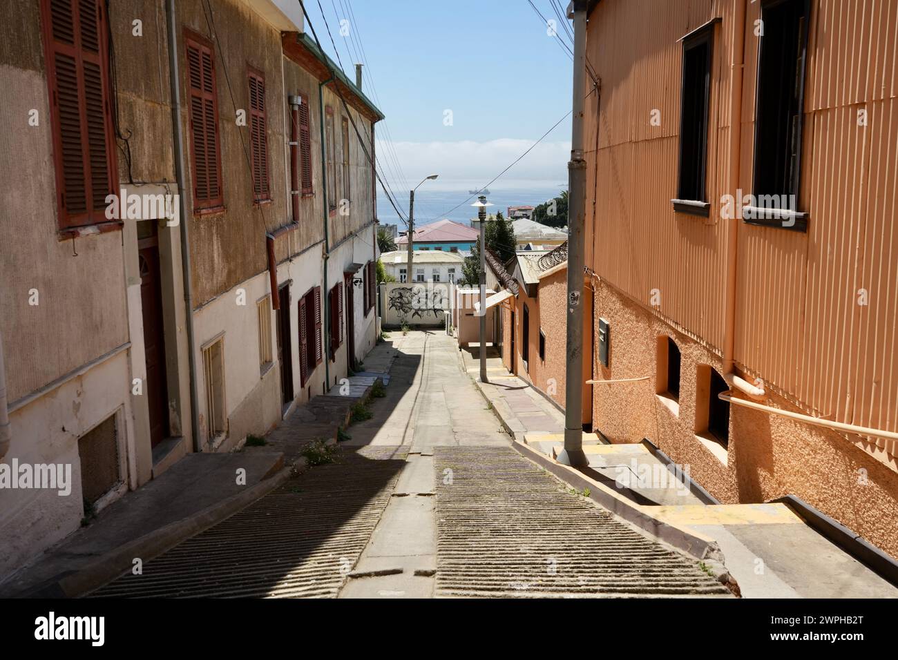 Blick auf die Straße auf traditionelle braune Gebäude mit dem Meer im Hintergrund. Stockfoto