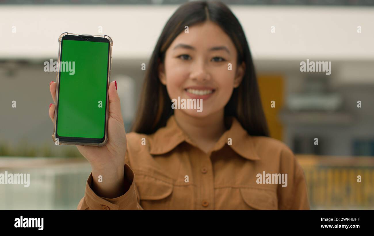 Handy Gerät Fokus verschwimmen asiatische Geschäftsfrau chinesisches Mädchen halten Smartphone grün Modell Glückliche Geschäftsfrau Werbung Handy Chroma Schlüssel Stockfoto