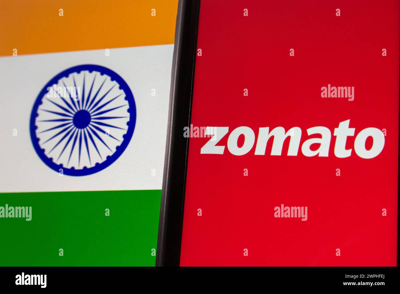 Zomato-Logo auf dem iPhone-Bildschirm auf dem Hintergrund der indischen Flagge. Zomato ist ein indischer multinationaler Restaurantlieferant und Lebensmittellieferant Stockfoto