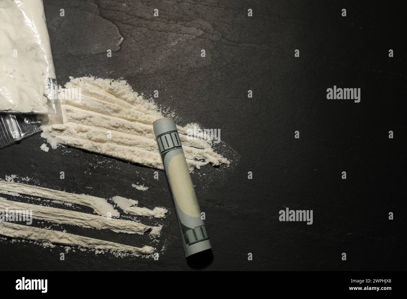 Plastiktüte mit harter Droge und gerollter Dollar-Banknote auf grauem, strukturiertem Hintergrund, flache Lay. Leerzeichen für Text Stockfoto