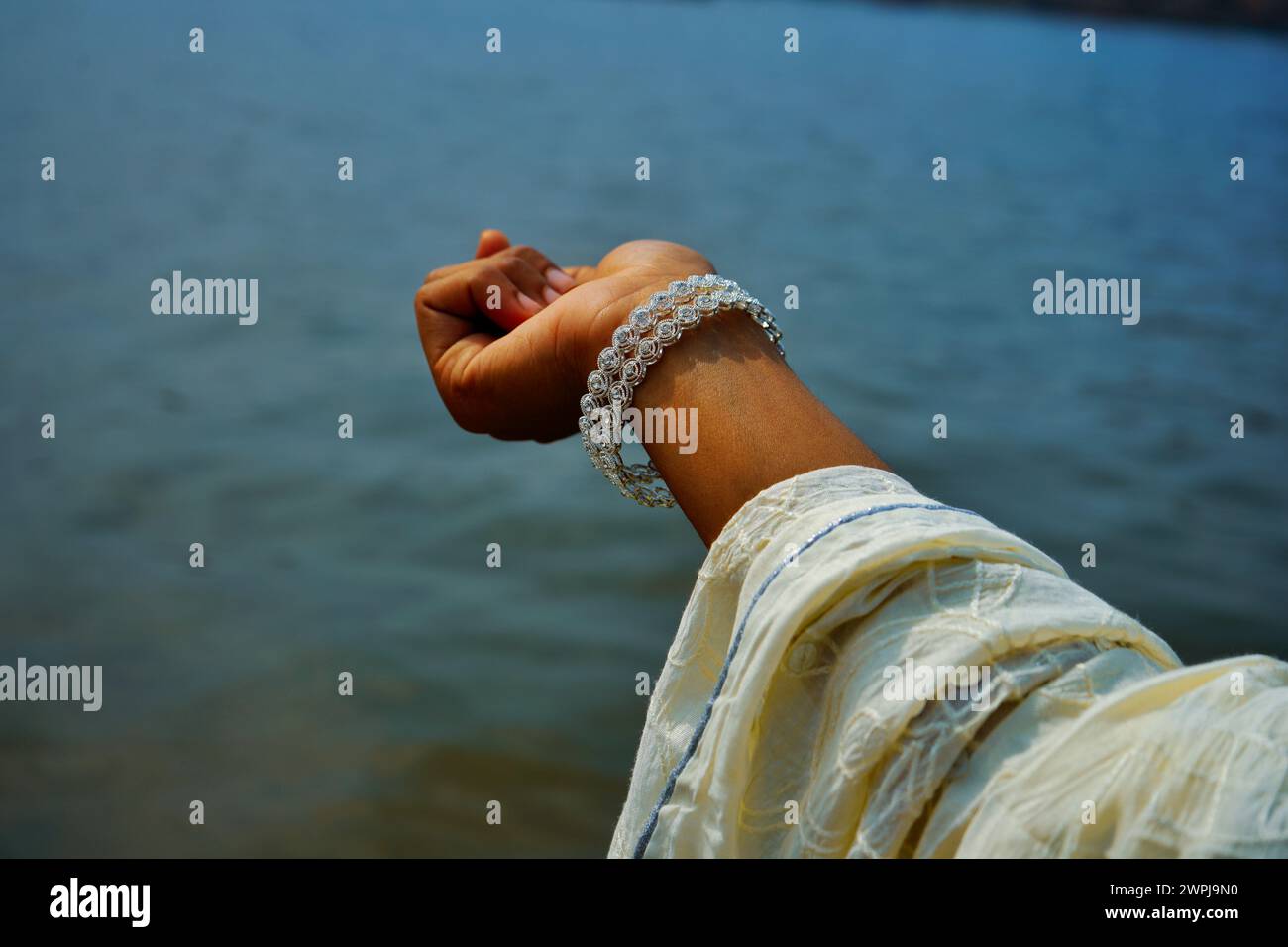 Frauen tragen silberne Armreifen im Handgelenk, die sich Richtung Fluss zeigen. Stockfoto