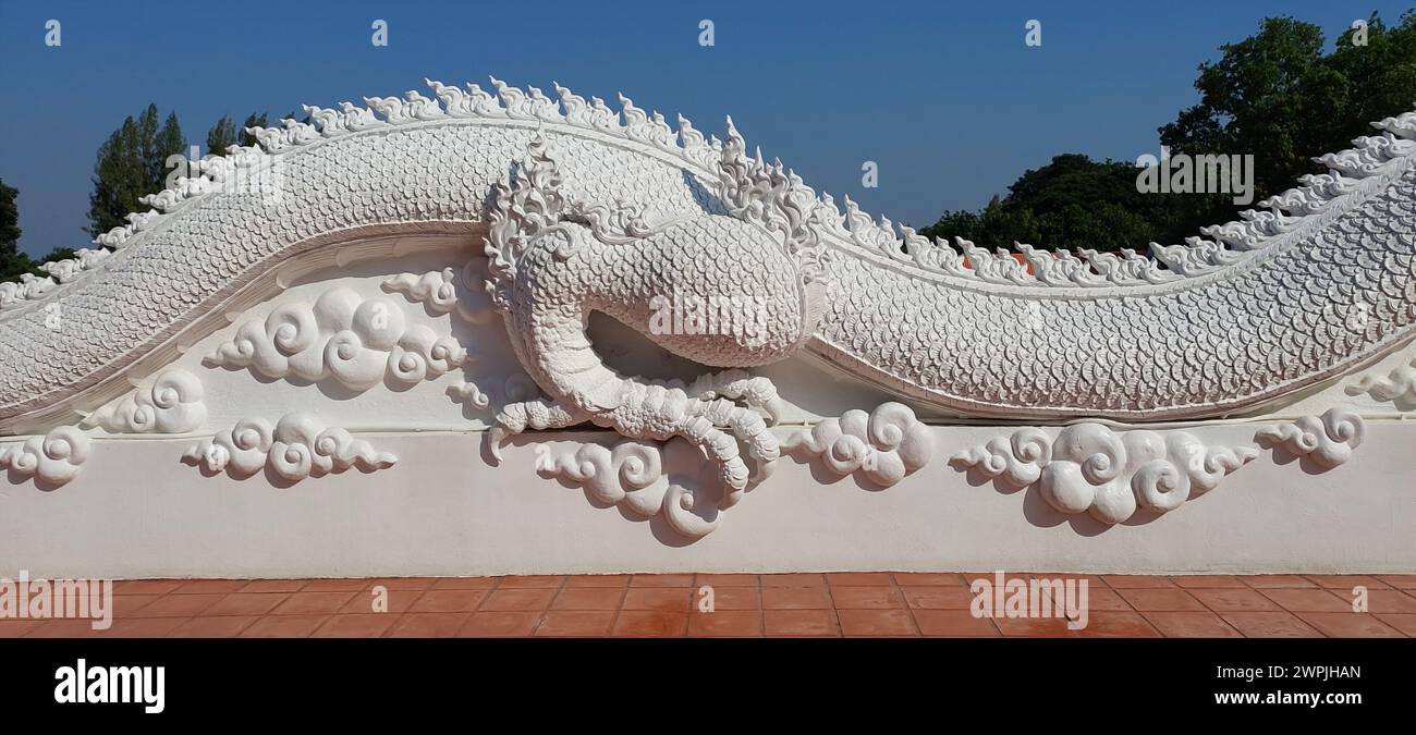 Dreidimensionales Stuckmuster im thailändischen Stil auf einem weißen Drachenkörper, eine Wolkenwand im Kontrast zum Himmel. Stockfoto