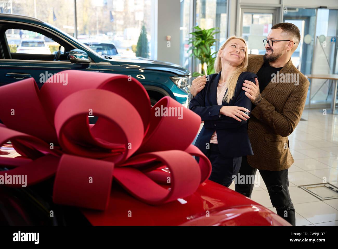 Der Mann stellt seiner Frau ein Auto vor Stockfoto