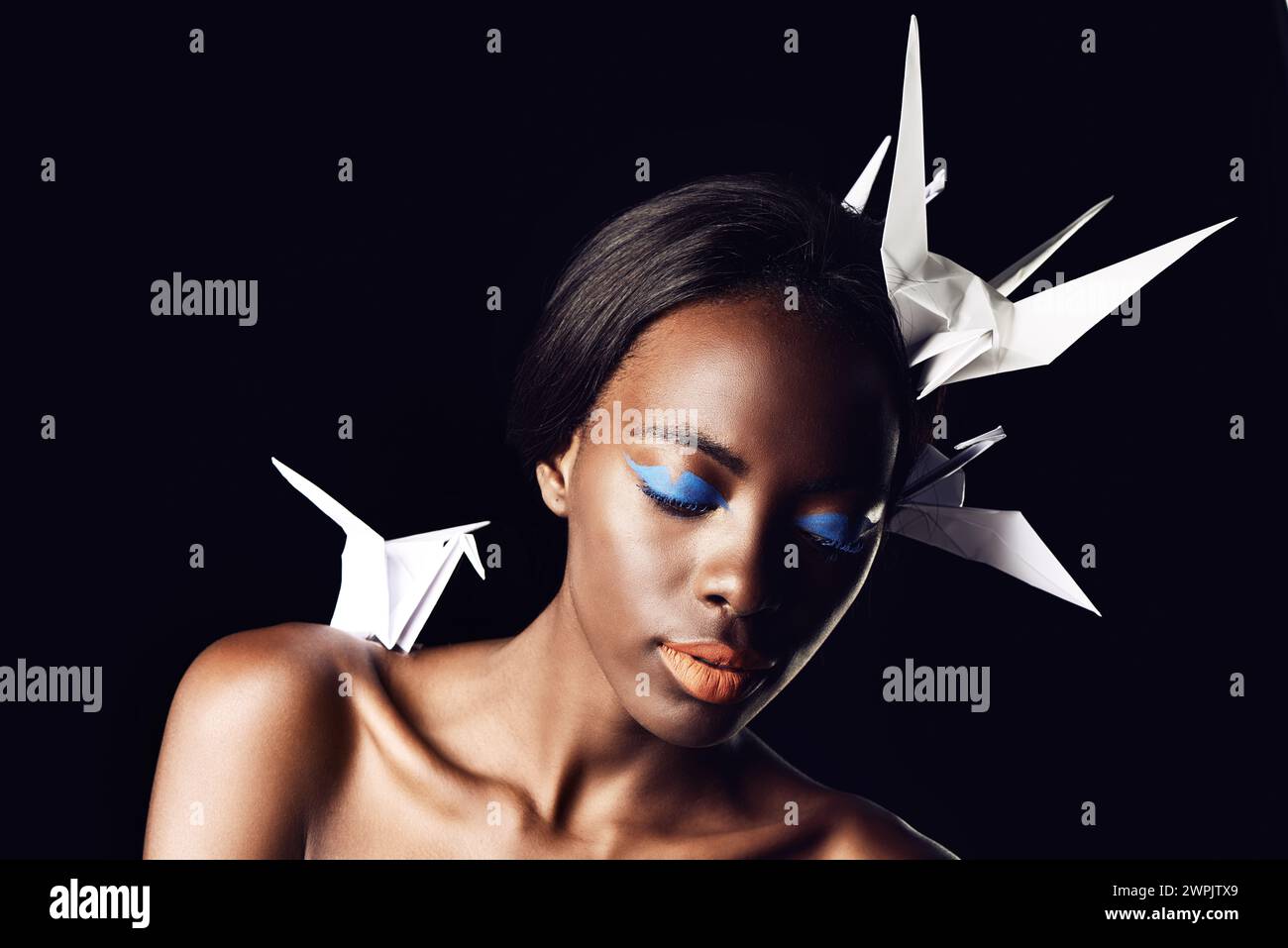 Schwarze Frau, Make-up und schöne Kunst mit Schönheit, Kosmetik oder Origami-Vögeln auf dunklem Studiohintergrund. Nahaufnahme oder Gesicht einer afrikanischen weiblichen Person oder Stockfoto