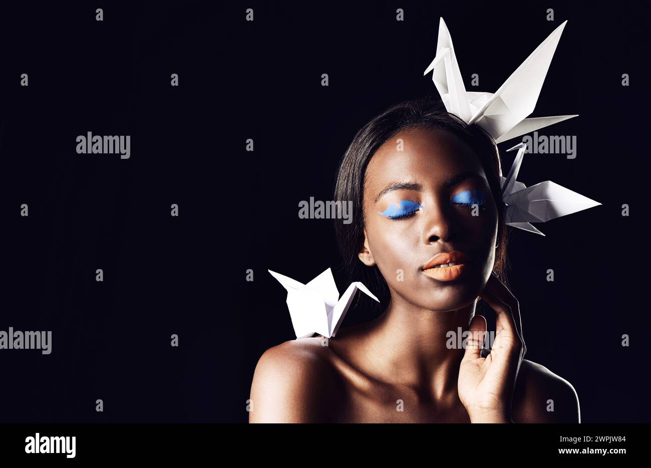 Schwarze Frau, Make-up und schöne Kunst mit Schönheit, Origami-Vögeln oder Kosmetik auf dunklem Studiohintergrund. Nahaufnahme oder Gesicht einer afrikanischen weiblichen Person oder Stockfoto