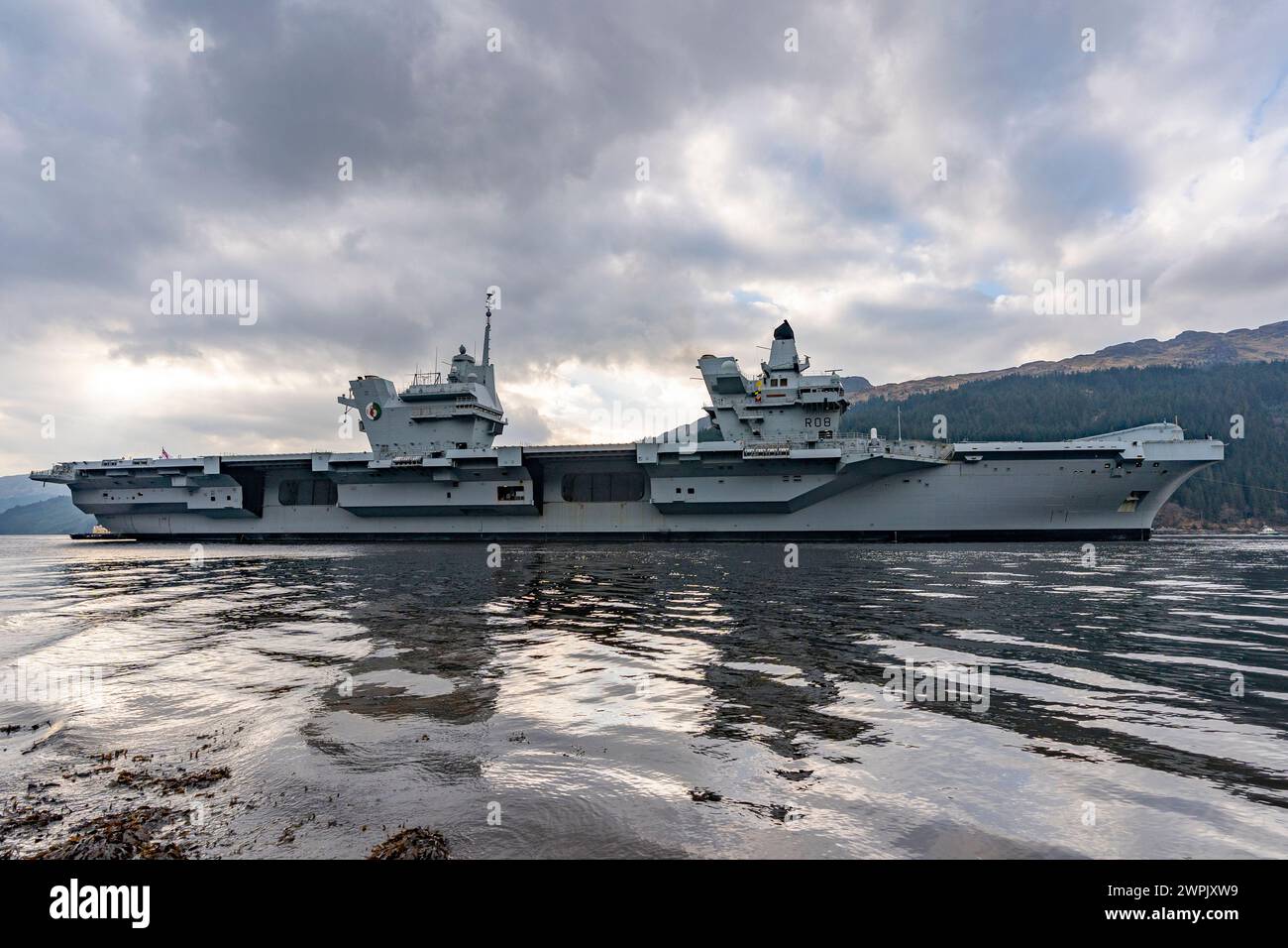 Glen Mallan, Argyll and Bute, Schottland, Großbritannien. März 2024. Die Royal Navy Flugzeugträger HMS Queen Elizabeth trifft heute in Glen Mallan auf Loch Long ein, um Munition abzuladen, bevor sie zur Rosyth Dockyard fährt, um ihre Propellerkupplungen zu reparieren. Iain Masterton/Alamy Live News Stockfoto