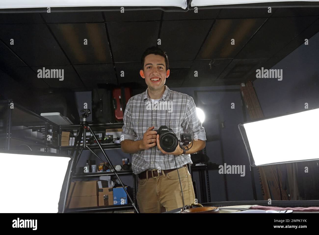 Ein professioneller Fotograf posiert im Studio und hält eine Digitalkamera in der Hand. Er ist bereit für das Fotoshooting. Stockfoto