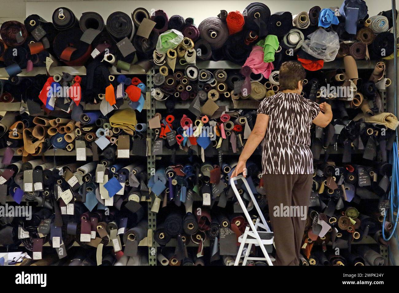 Weibliche Wahl von Stoffrollen in der Textilfabrik. Stockfoto