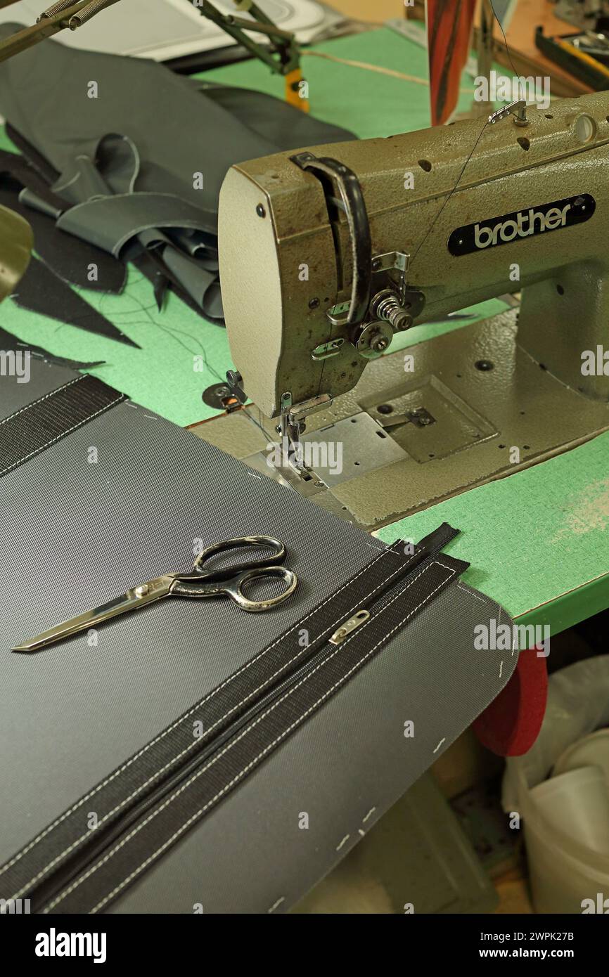 Reparatur oder Austausch des Reißverschlusses mit einer Vintage-Nähmaschine in der Werkstatt. Stockfoto