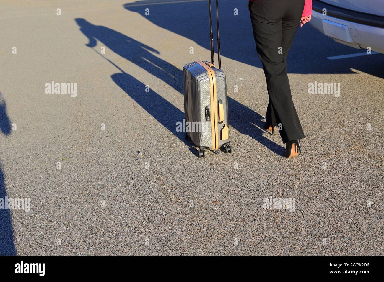 Nahaufnahme von weiblichen Beinen einer Geschäftsfrau, die High Heels trägt und Gepäck vor den Flughafen schleppt Stockfoto