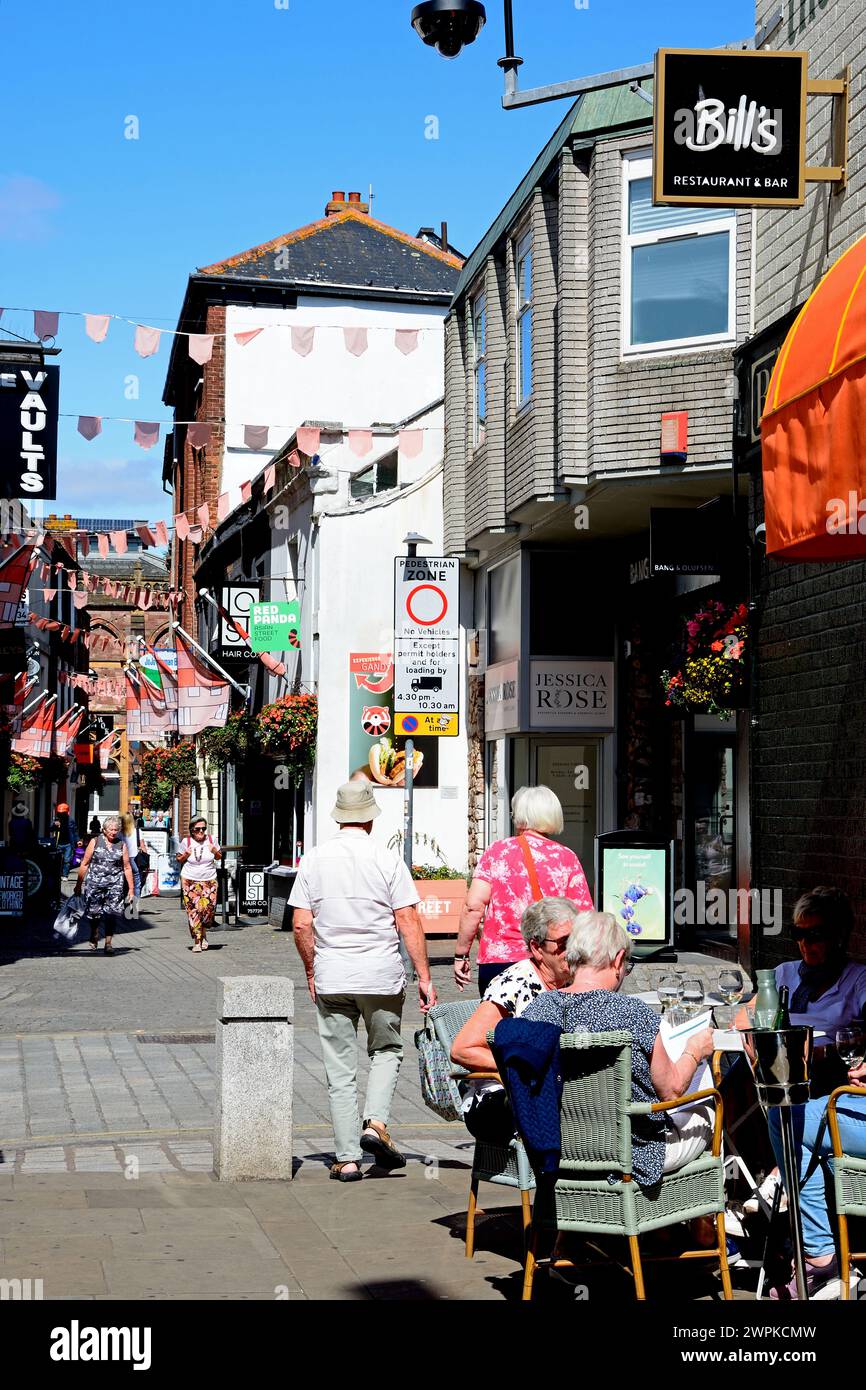 Die Leute entspannen sich in einem Straßencafé entlang der Gandy Street mit einem Teil des Royal Albert Memorial Museum und der Art Gallery auf der Rückseite, Exeter, Devon, Großbritannien. Stockfoto
