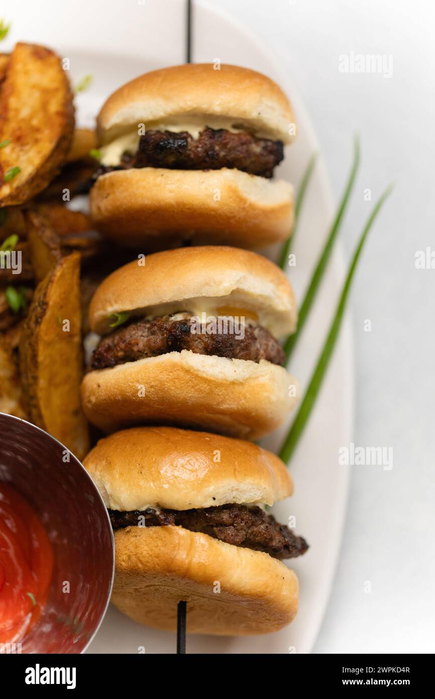 Leckere Mini-Hamburger-Slider auf weißem Teller mit Ketchup und Wedges Stockfoto