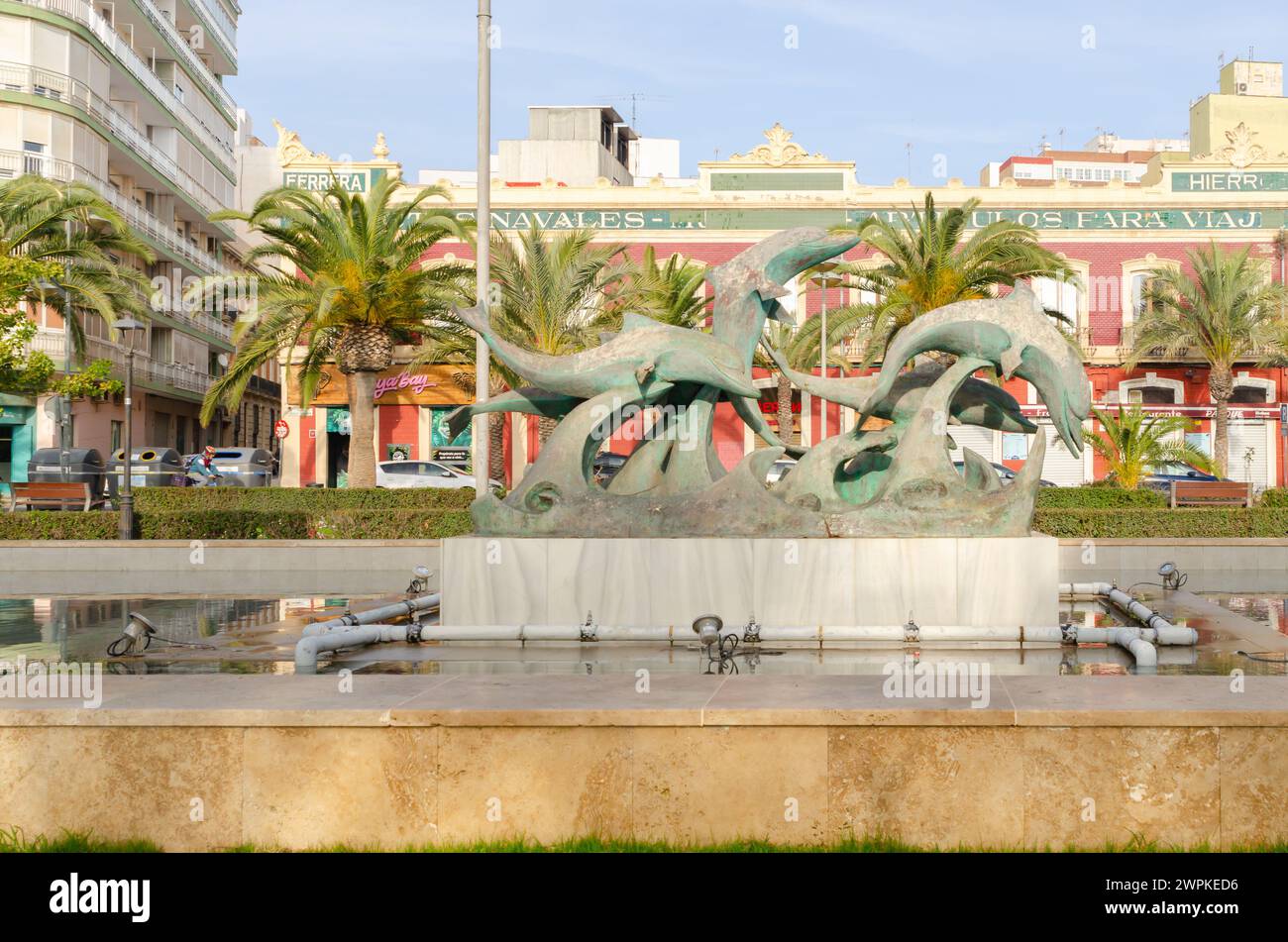 ALMERIA, SPANIEN - 11. DEZEMBER 2023 die Skulptur zeigt fünf wunderschöne Delfine, die auf den Wellen spielen. Sie befindet sich in der Mitte eines rechteckigen Brunnens Stockfoto