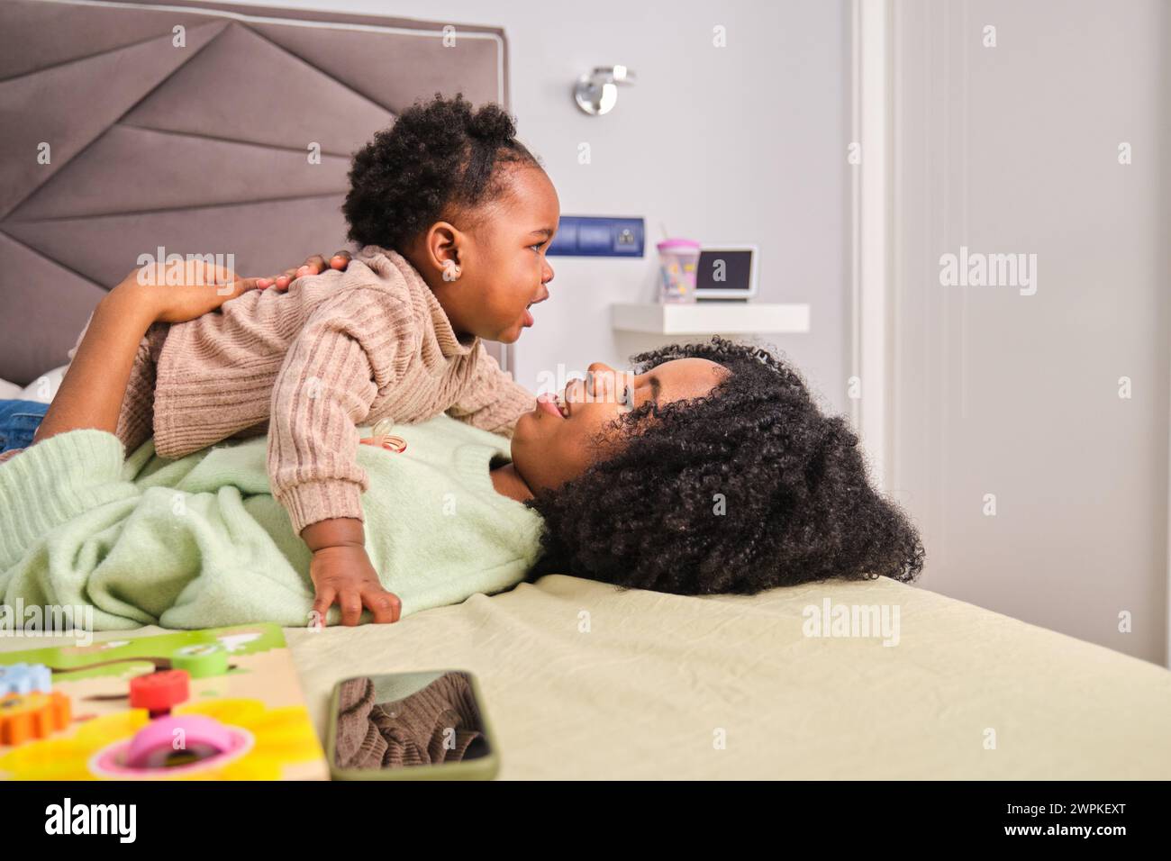 Kubanische Mutter umarmt ihre Tochter im Bett zu Hause. Stockfoto