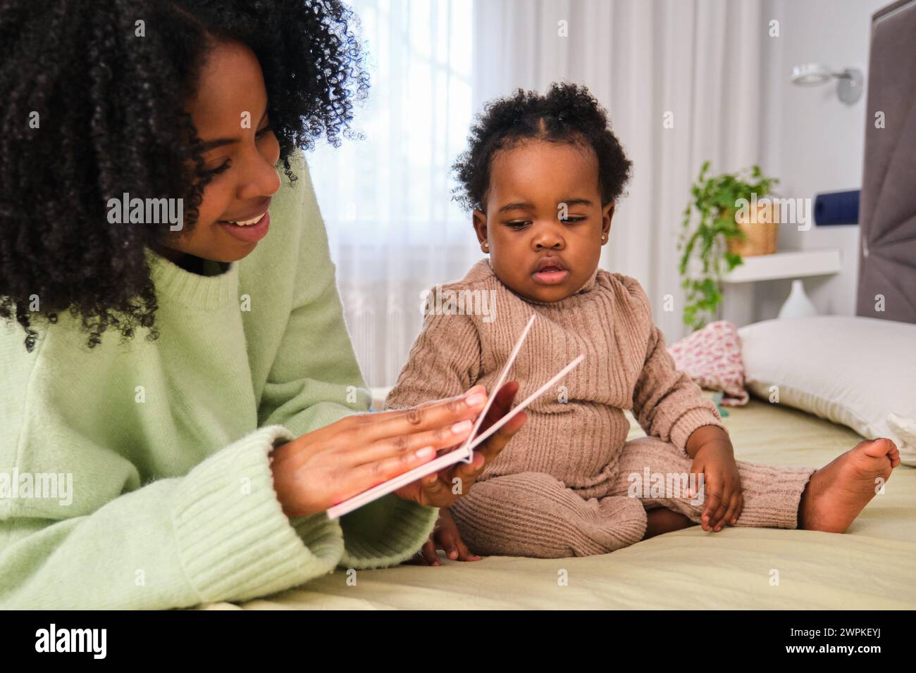 Die kubanische Mutter liest ihrer Kleinkind-Tochter ein Kinderbuch. Stockfoto