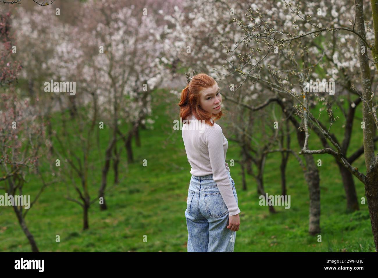 Frühling wunderschönes, romantisches rothaariges Mädchen, das im blühenden Garten steht. Stockfoto