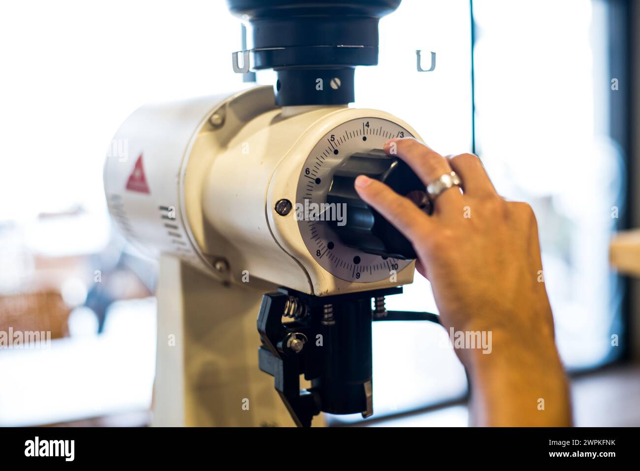 Ein industrieller Kaffeemühle mit Händen passt die Größe an Stockfoto