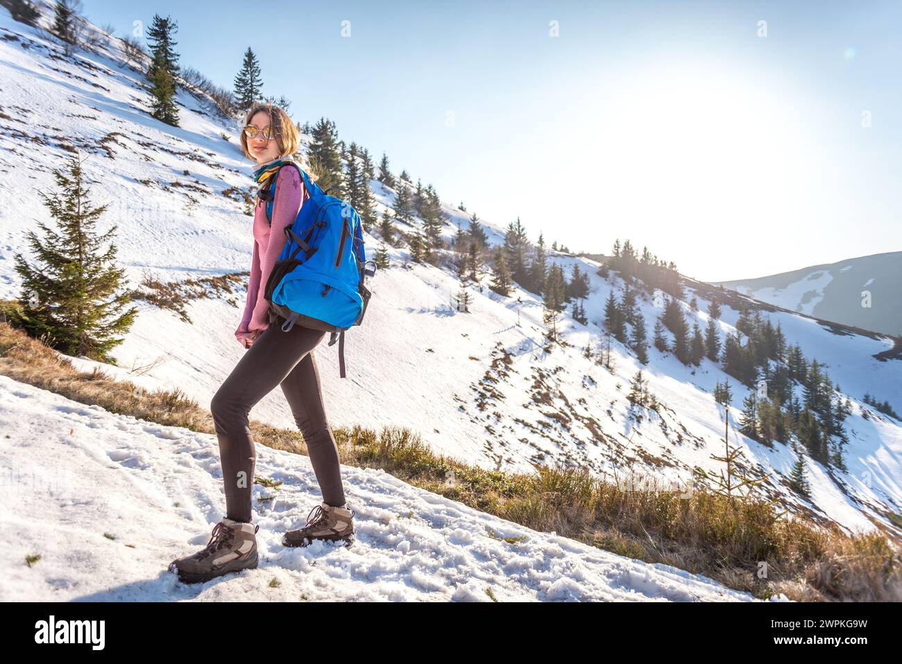 Junge Frau mit Rucksack auf dem Trail in Snowy Mountain Stockfoto