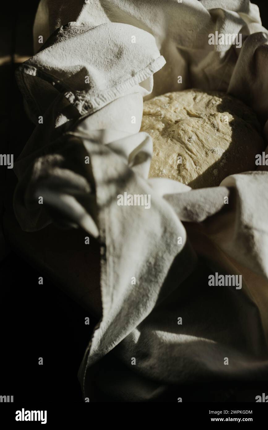 Brot in Schüssel mit Geschirrtuch auf Küchenarbeitsplatz bei Sonnenschein Stockfoto