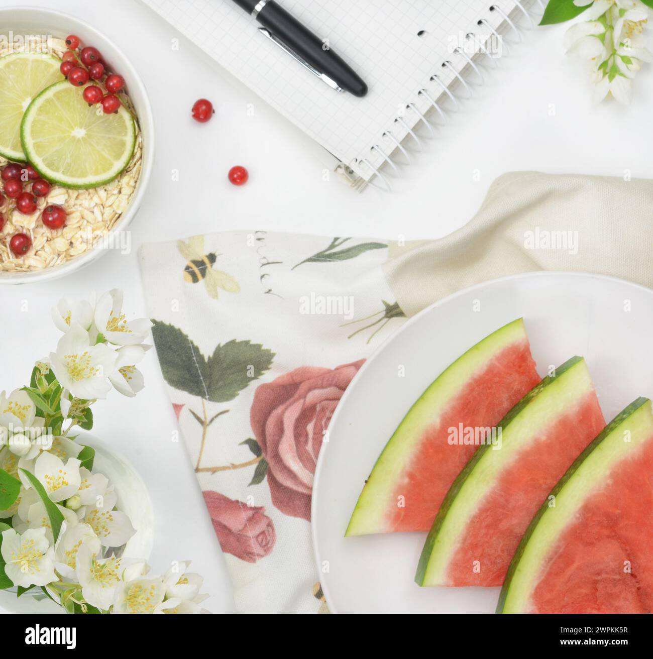 Tisch mit Blick von oben mit Früchten, Blumen und Müsli, helle Farben. Stockfoto