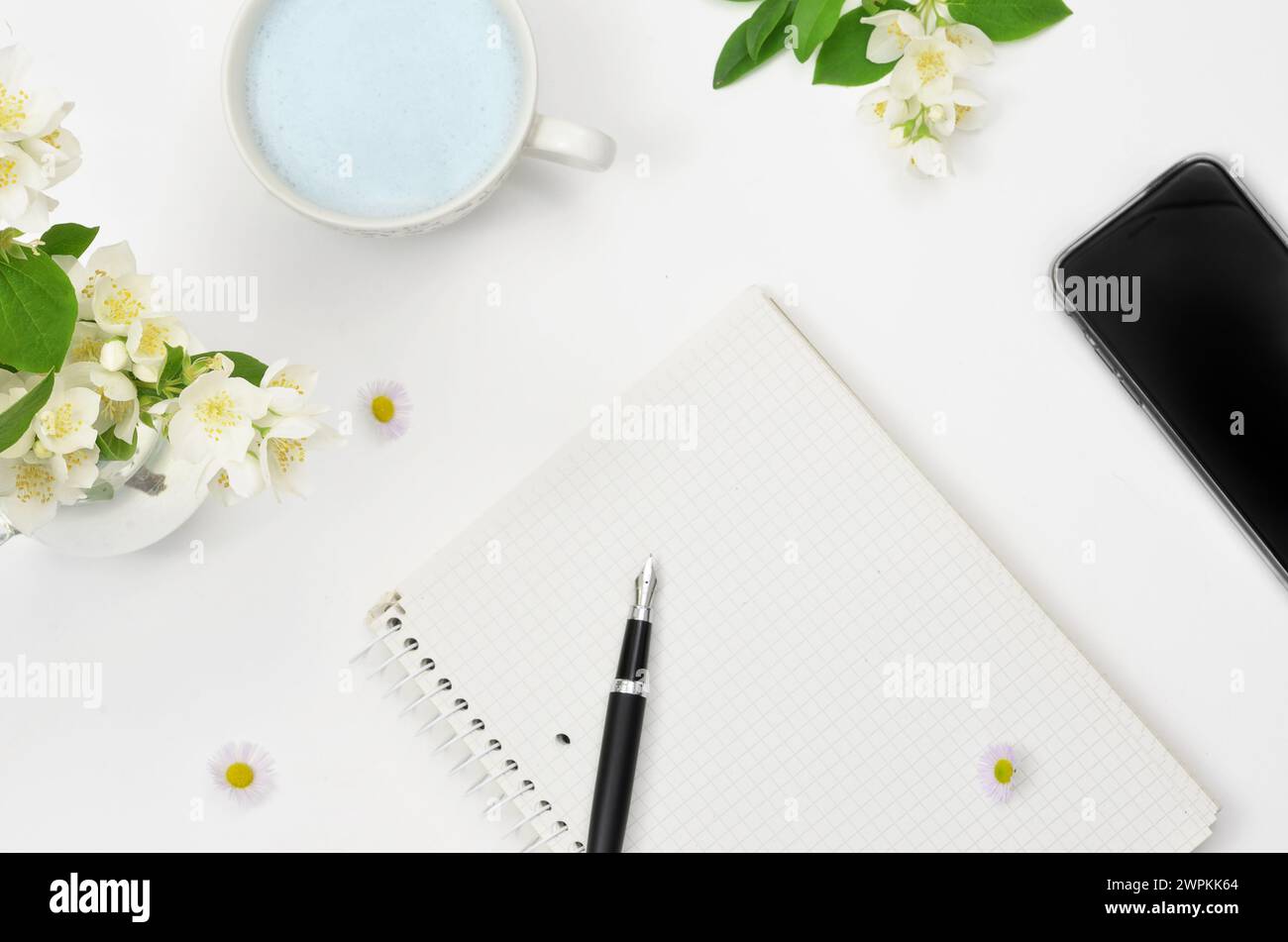 Schmetterling Erbsentee, Notizblock mit leerem Blatt zum Ausfüllen mit Inhalt, Stift, Blumen auf dem Tisch. Stockfoto