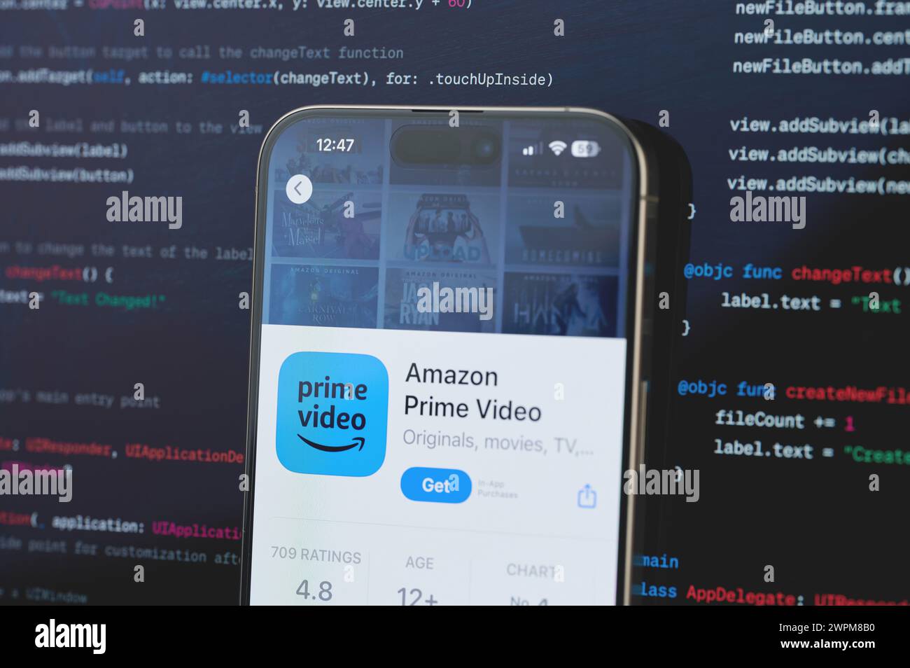 New York, USA - 23. Februar 2024: Amazon Prime Video auf dem iphone-Bildschirm mit unscharfem Code-Programmierhintergrund Stockfoto