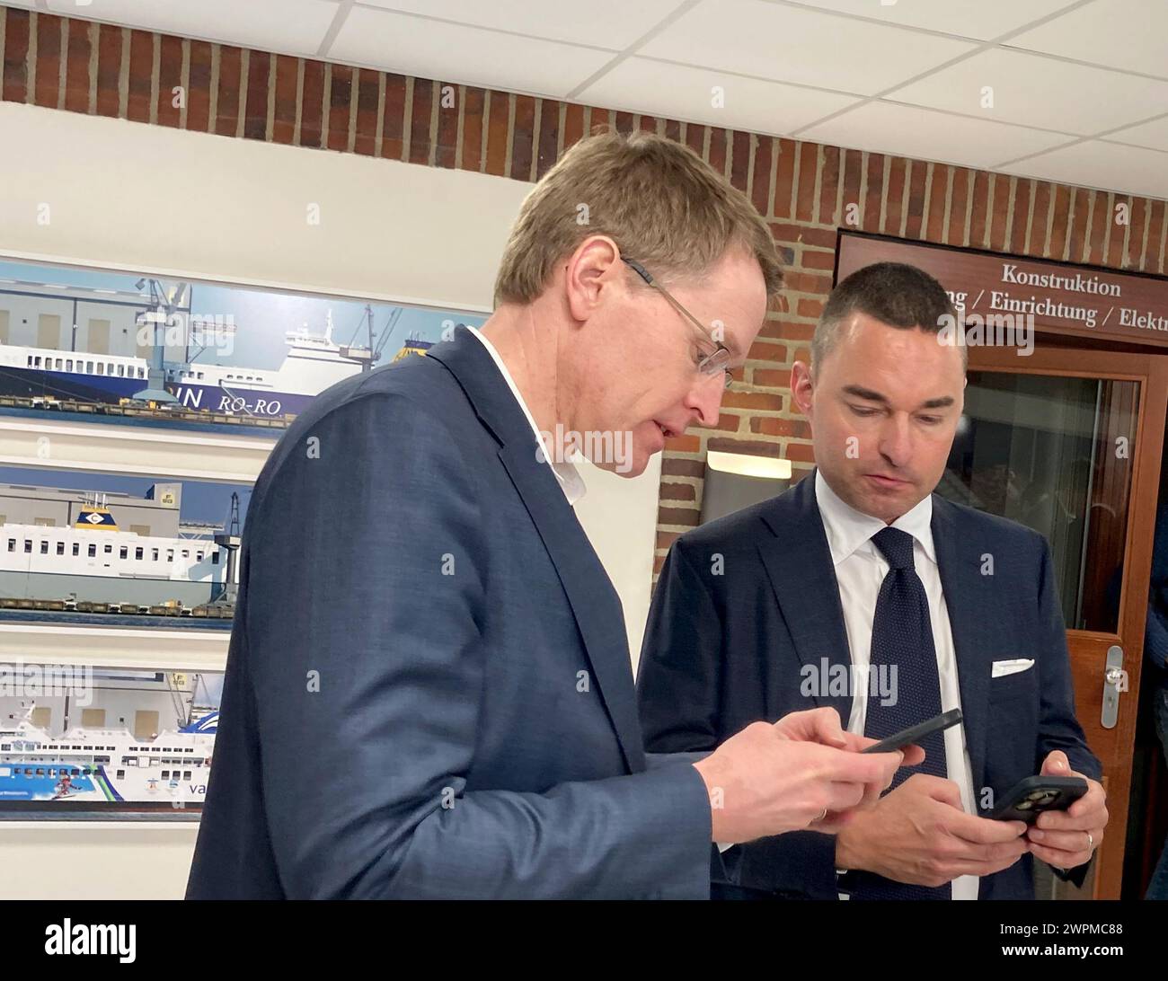 Flensburg, Deutschland. März 2024. Investor und Werftbesitzer Lars Windhorst (r) und Schleswig-holsteinischer Ministerpräsident Daniel Günther (CDU) schauen sich ihre Handys im Verwaltungsgebäude der Flensburger Schiffsbau-Gesellschaft an. Seit Monaten machen die beiden Werften des Investors Lars Windhorst hauptsächlich negative Schlagzeilen. Jetzt ist der Ministerpräsident gekommen, um sich über die Situation zu informieren. Quelle: Birgitta von Gyldenfeldt/dpa/Alamy Live News Stockfoto