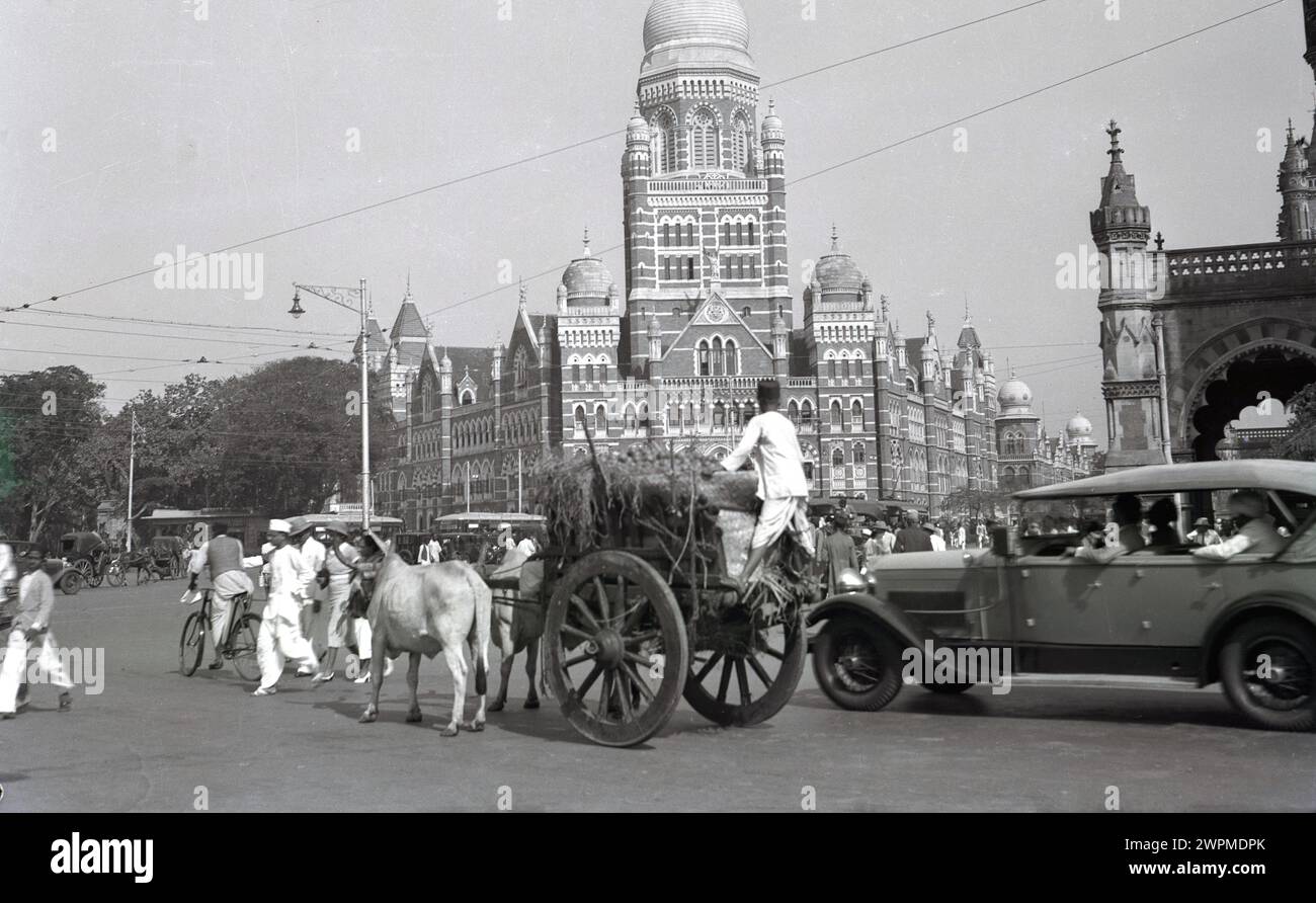 1930er Jahre, historische Straßenszene in der Altstadt von Karachi, wo alte Transportmittel, ein Ochse & Wagen, eine Straße mit dem neuen, einem Auto teilt. Ein großes Gebäude mit Kuppel auf dem Bild zeigt die islamische Kultur der Stadt, die im 8. Jahrhundert eingeführt wurde. In dieser Zeit war es Teil des Britisch-Indischen Reiches, wobei die Region in separate Provinzen, Sind, Punjab und die Baluchistan Agency aufgeteilt wurde. Im Jahr 1947 wurde es Teil Pakistans. Stockfoto