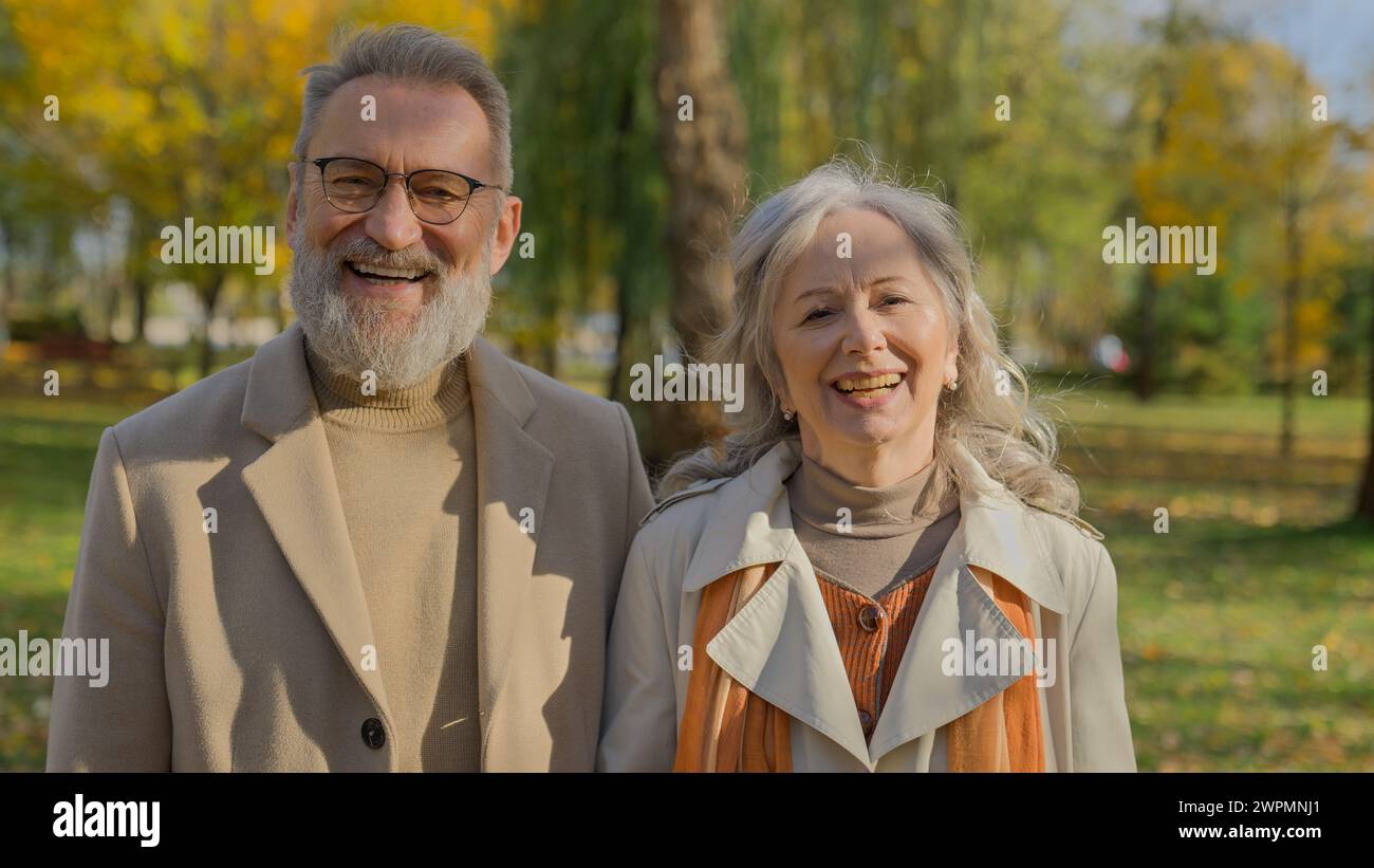 Porträt eines glücklichen, reiferen Paares lächelnd im Herbstpark fröhlicher alter Mann, der zusammen für die Kamera in der Natur posiert eleganter älterer Ehemann Stockfoto