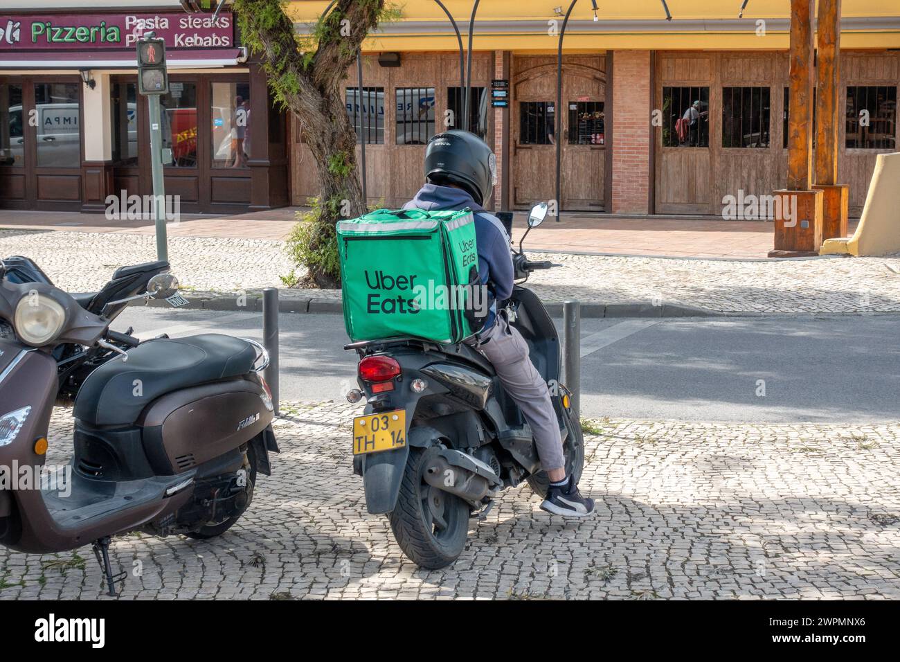 Ein Uber Eats Motorcycle Rider wartet auf Eine Abholbestellung in Albufeira Portugal am 6. März 2024 Stockfoto
