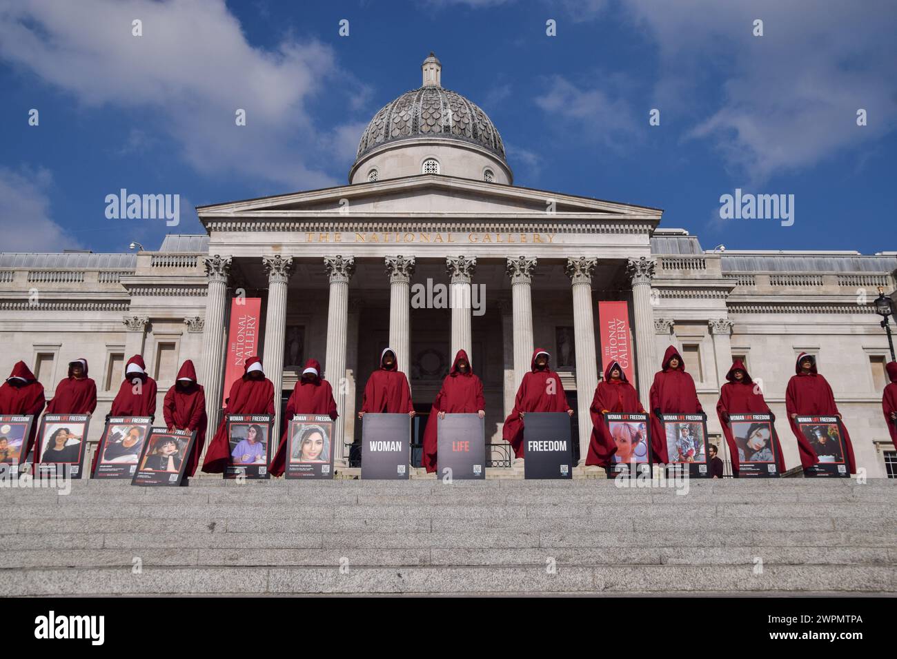 Demonstranten stehen auf dem Trafalgar Square mit Bildern der Opfer des iranischen Regimes während der Demonstration. Frauen in den Kostümen der Magd's Tale zogen am Internationalen Frauentag durch die Londoner Innenstadt, um die Freiheit des Iran zu unterstützen. (Foto: Vuk Valcic / SOPA Images/SIPA USA) Stockfoto