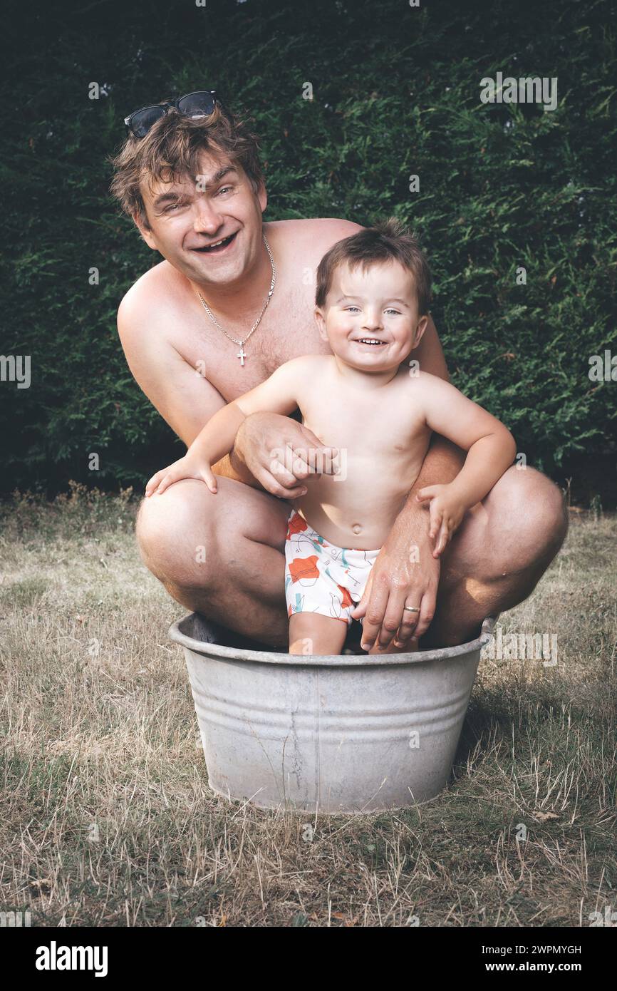 Vater und Sohn chillen in einer kleinen Retro-Blechbadewanne Stockfoto