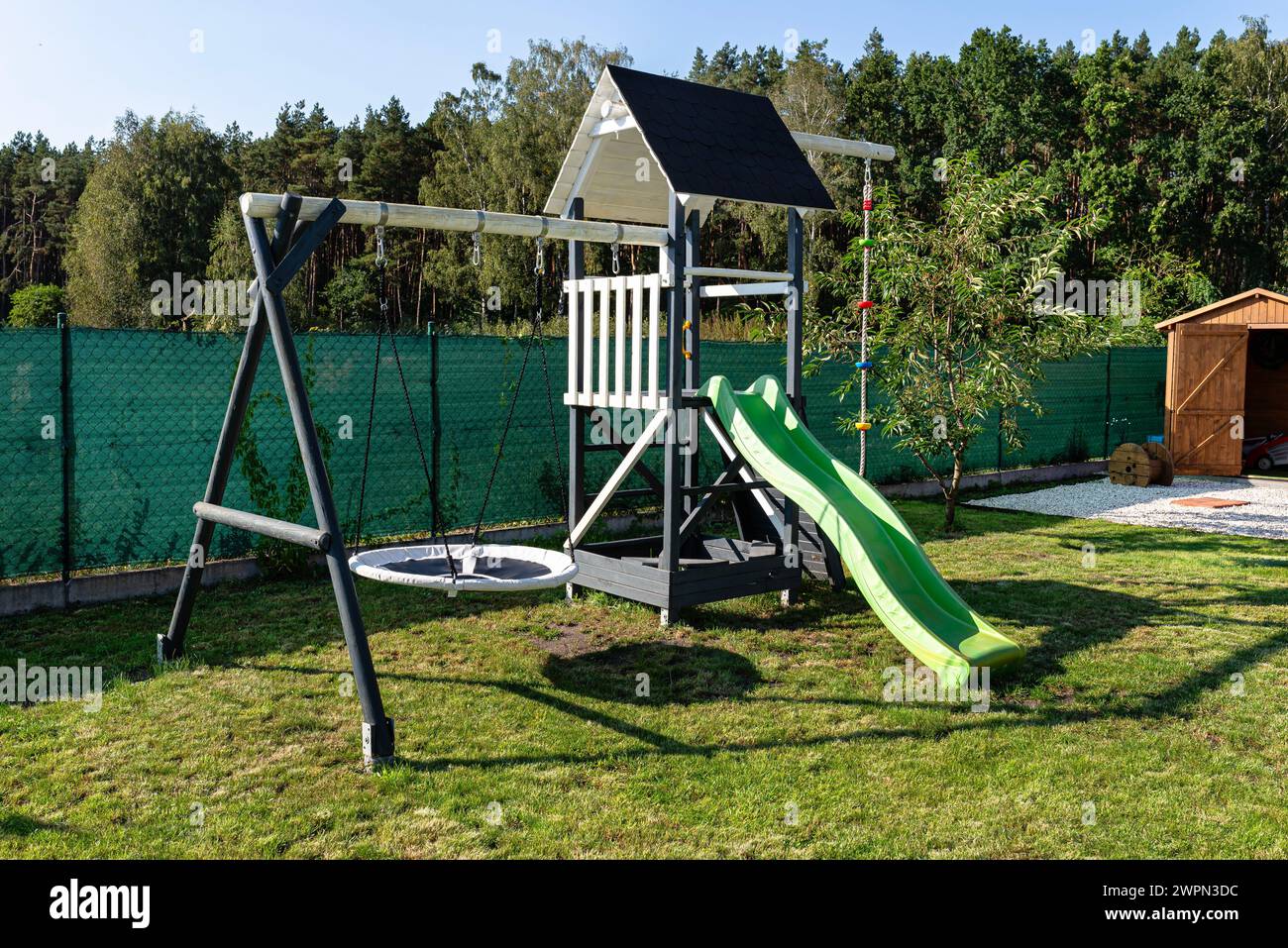 Ein Kinderspielplatz aus Holz, weiß und marineblau bemalt, steht im Garten. Stockfoto