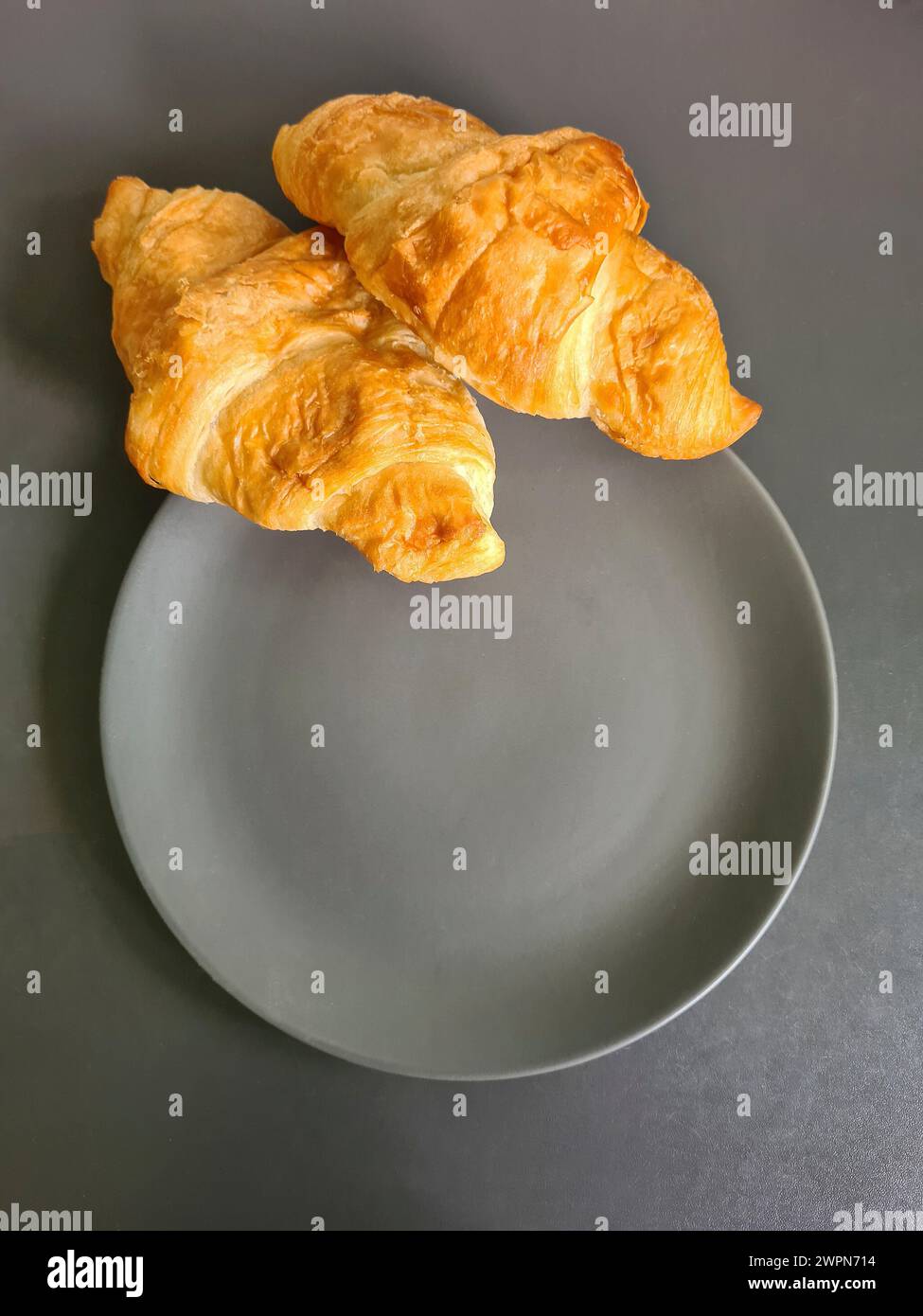 Zwei Croissants auf einem grauen Teller als kleiner Snack zwischen den Mahlzeiten Stockfoto