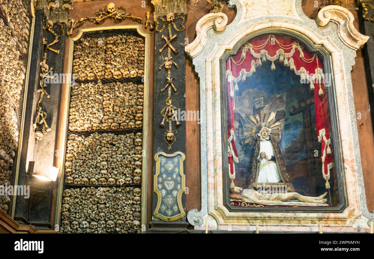 Ein katholischer Schrein zwischen angeordneten Schädeln und Knochen im Ossuar in der Chiesa di San Bernardino alle Ossa, Mailand, Italien Stockfoto