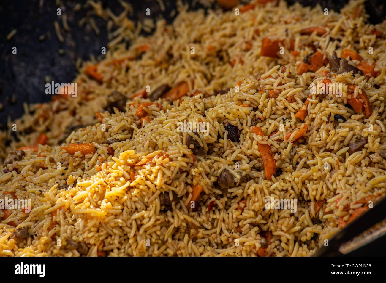 Heißer Pilaf in großem Kessel im Freien. Traditionelle orientalische Küche. Street Food Konzept. Nahaufnahme Stockfoto