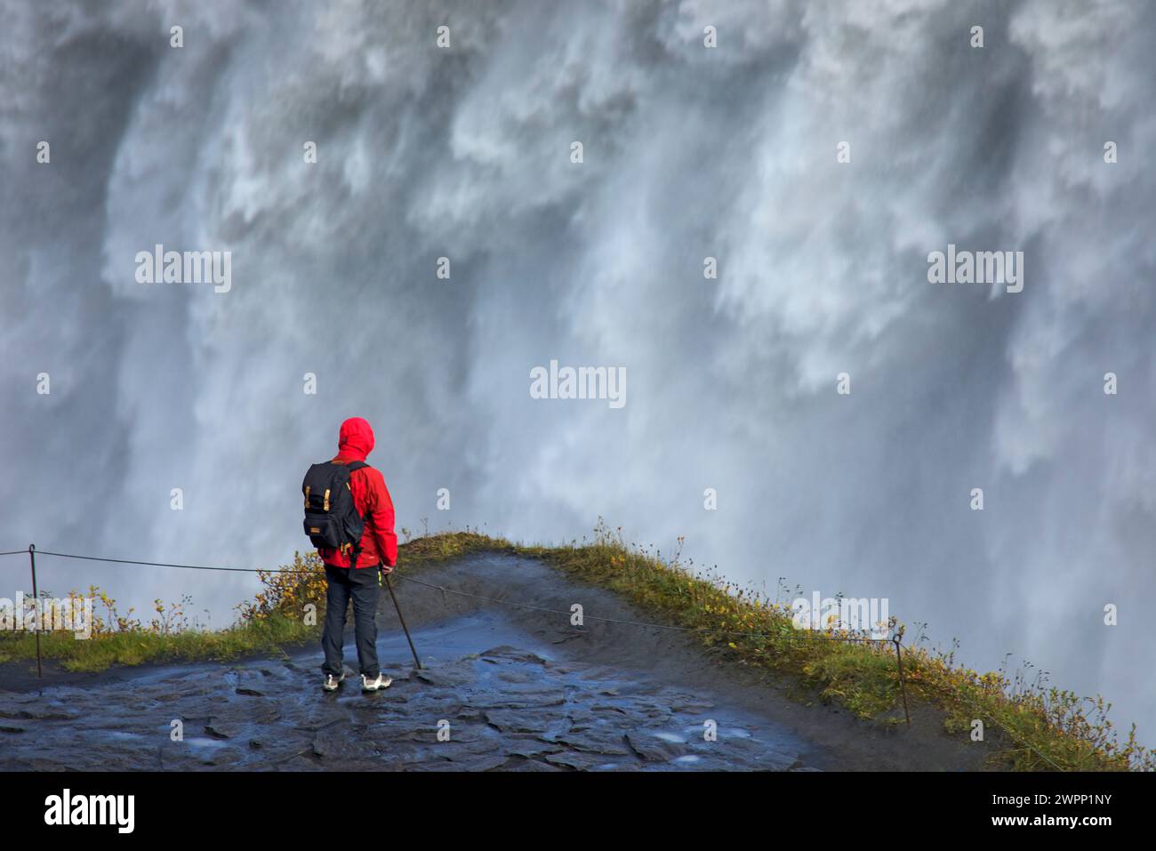 Mann mit roter Jacke vor den Wassermassen von Dettifoss Stockfoto