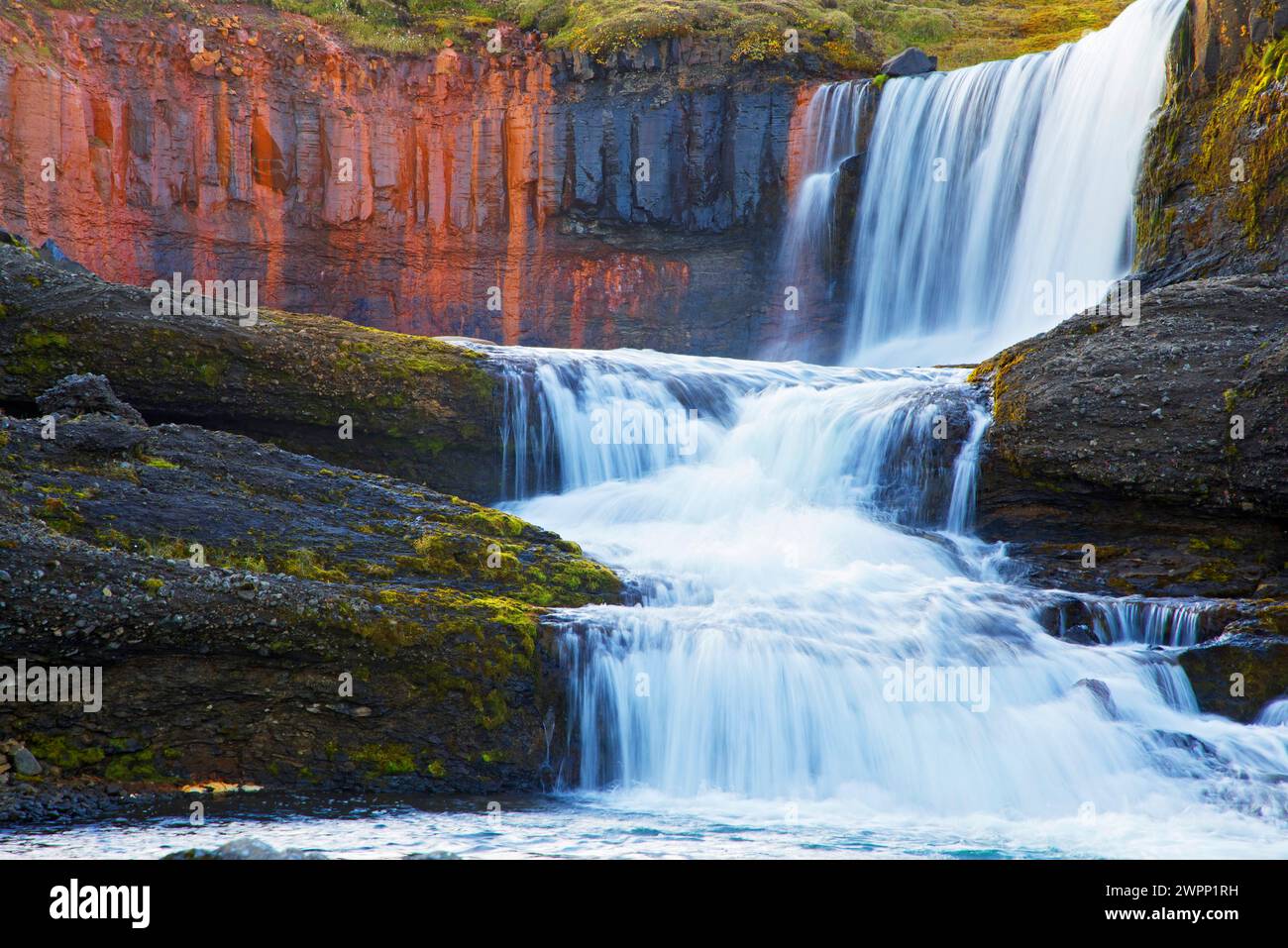 Slaidufoss (Veil Falls) fällt über Basaltsäulen, die durch Eisenoxid rot gefärbt sind, im kleinen Fluss Laugara bei Laugarfell nahe Mount Snaefell im Nordosten Islands. Stockfoto
