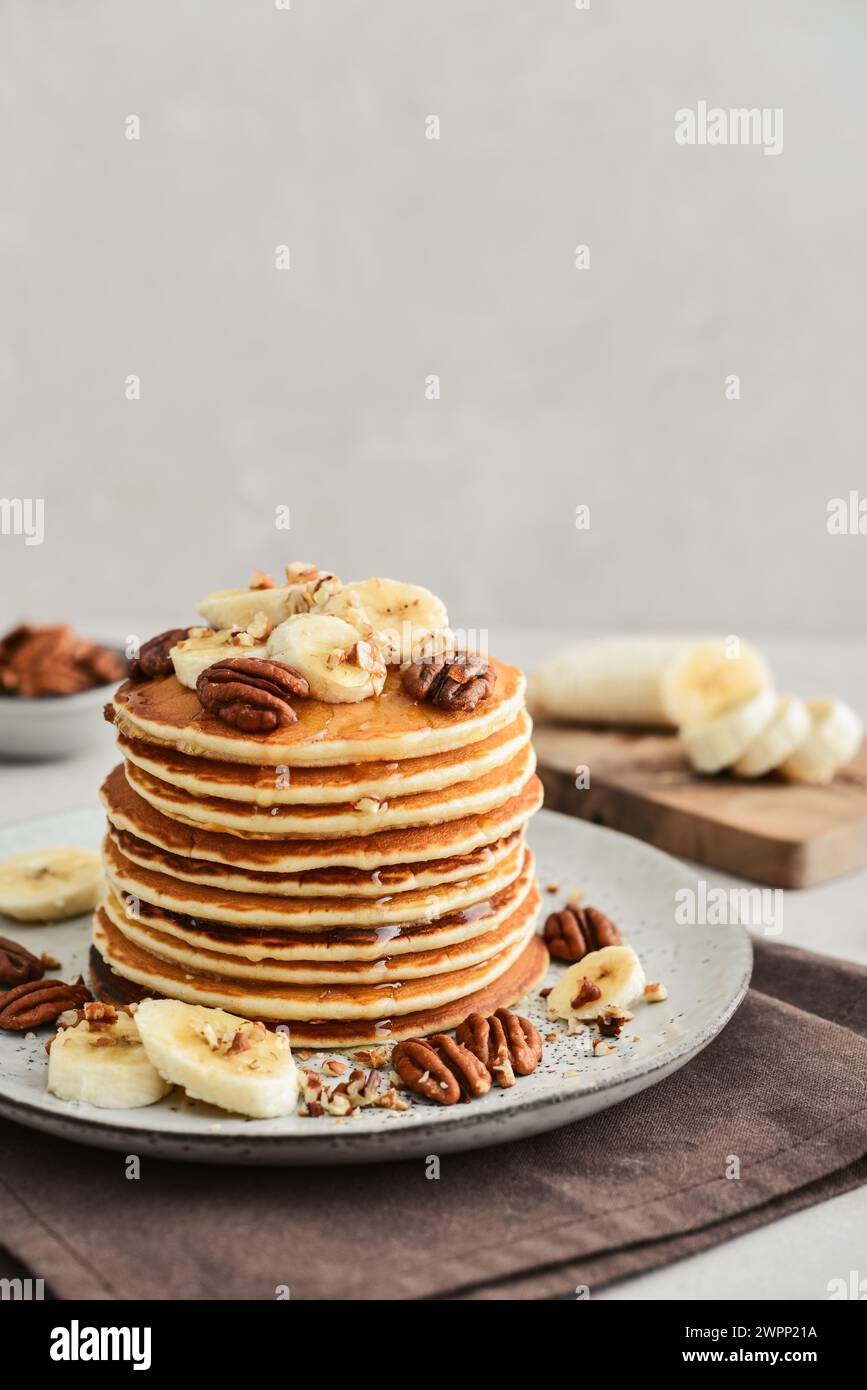 Teller mit Ahorn-Pekannkuchen mit frischen Bananen und Kaffee im Hintergrund. Stockfoto