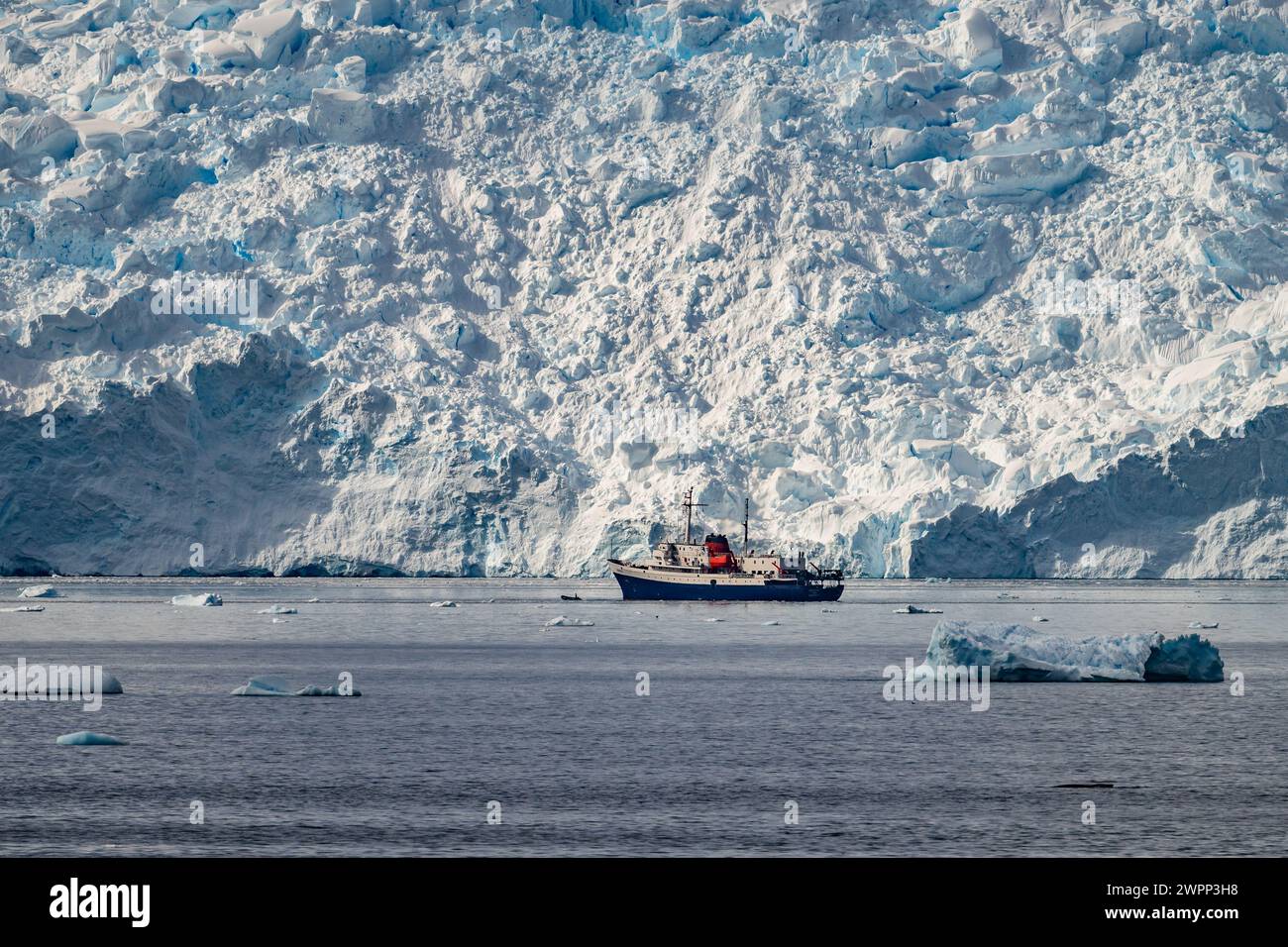 Ein Ausflugsboot am Fuße eines riesigen Gletschers. Antarktis. Stockfoto