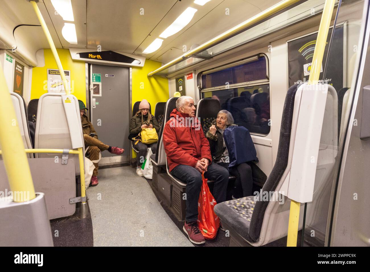 Passagiere, die in einem Zug der Baureihe 507 von Merseyrail mit Fahrgästen und Zuginnenraum reisen Stockfoto