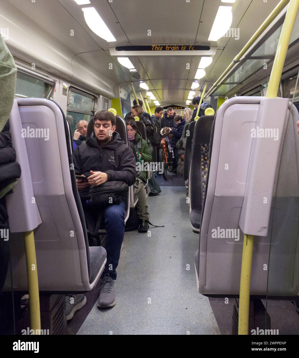 Passagiere, die in einem Zug der Baureihe 507 von Merseyrail mit Fahrgästen und Zuginnenraum reisen Stockfoto