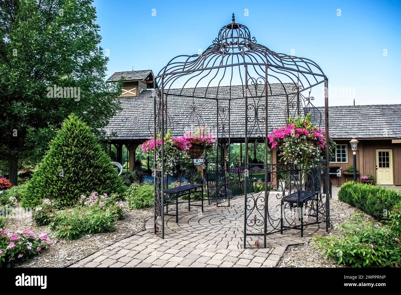 Hübscher Eisengarten-Pavillon mit Topfblumen in Panola Valley Gardens, einem Veranstaltungsort für Hochzeiten, in Lindstrom, Minnesota, USA. Stockfoto