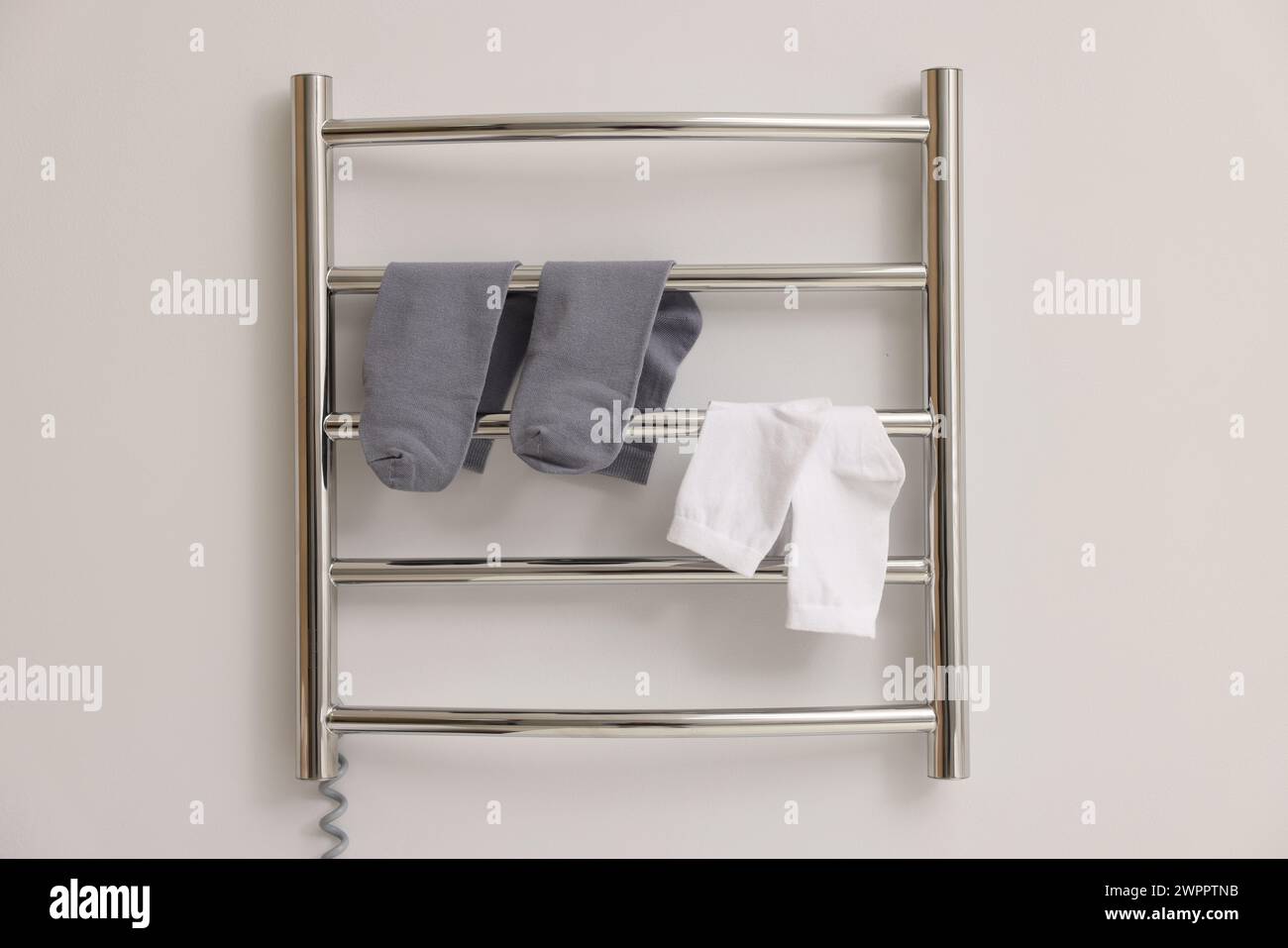 Beheizter Handtuchhalter mit Socken an weißer Wand Stockfoto
